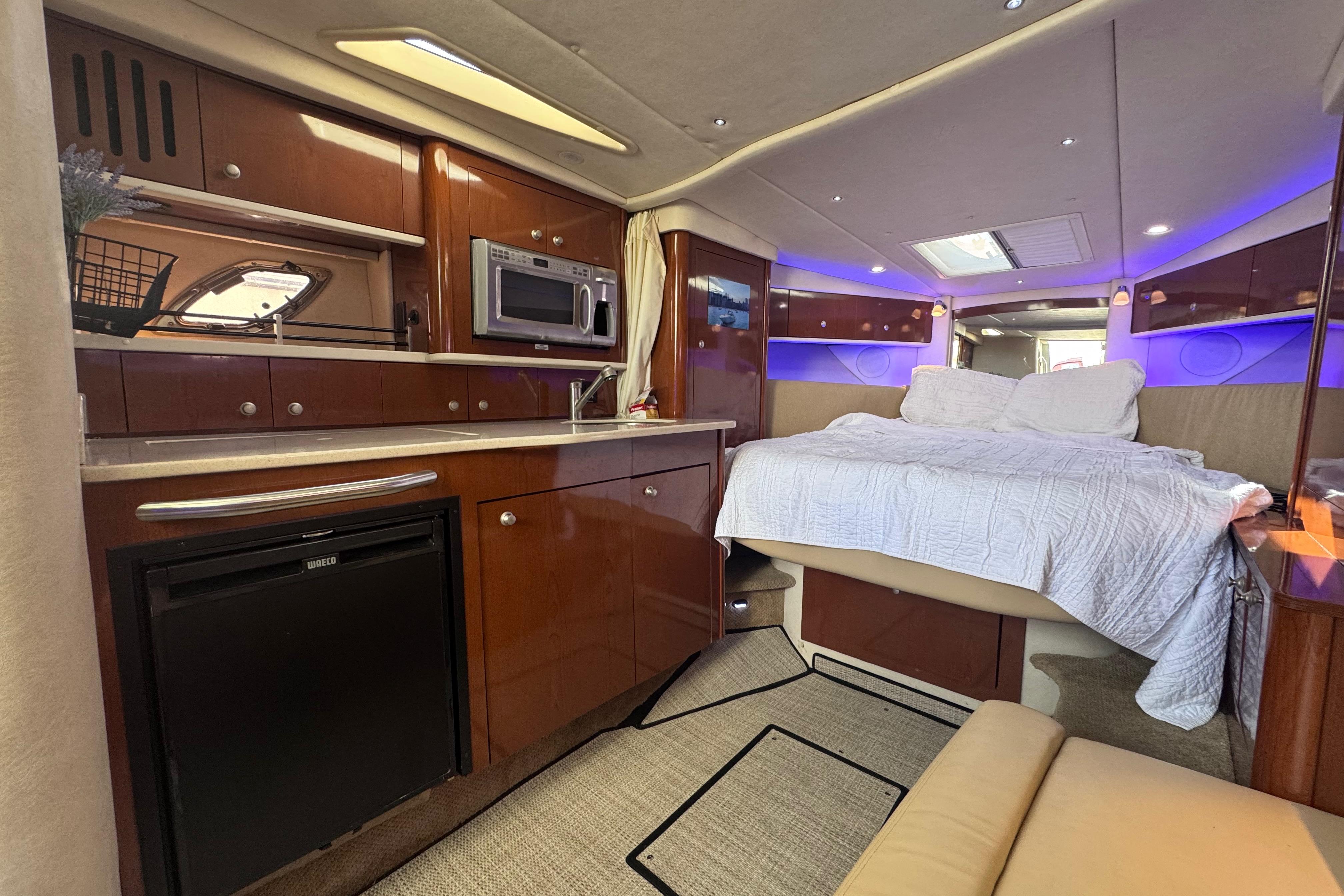 Luxurious interior of 2008 Sea Ray 350 Sundancer yacht with bed, kitchenette, and ambient lighting.