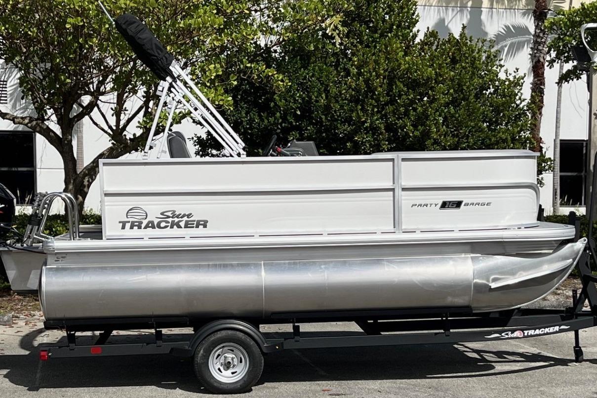 2026 Sun Tracker Party Barge 16 DLX pontoon boat on trailer, parked outdoors.