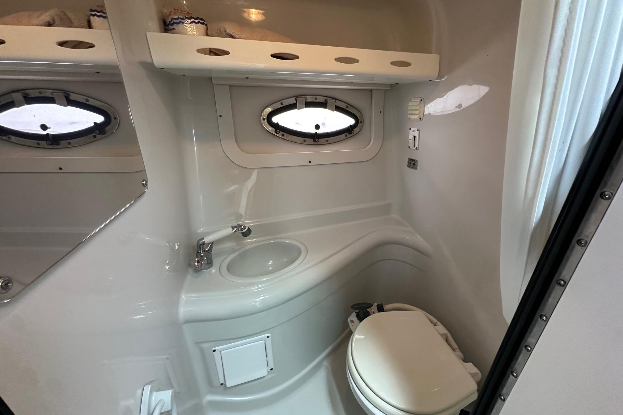 2008 Crownline 250 CR boat bathroom with sink, toilet, and porthole window.