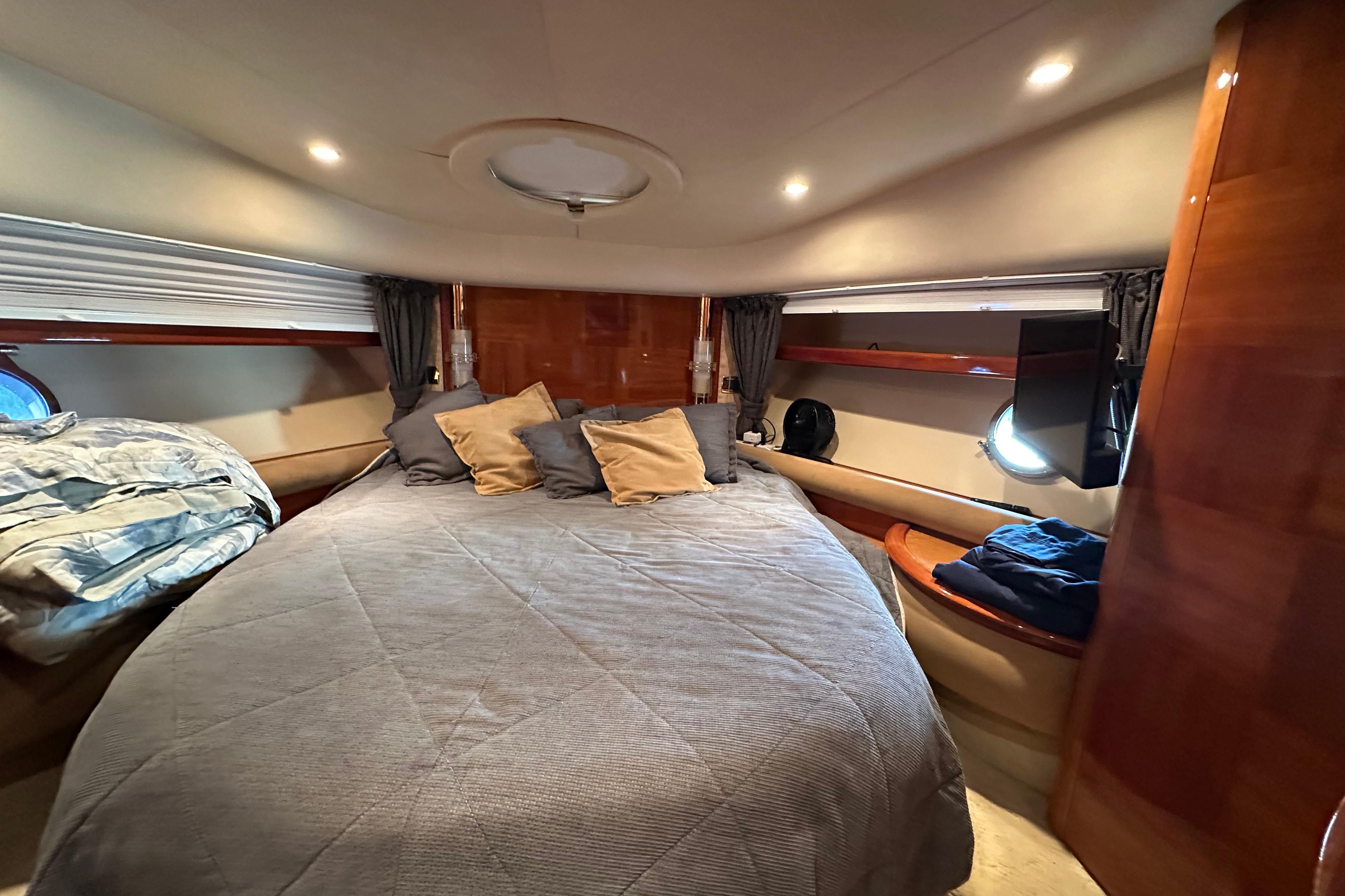 Luxurious bedroom interior of 2004 Azimut 55E yacht with cozy bedding and ambient lighting.