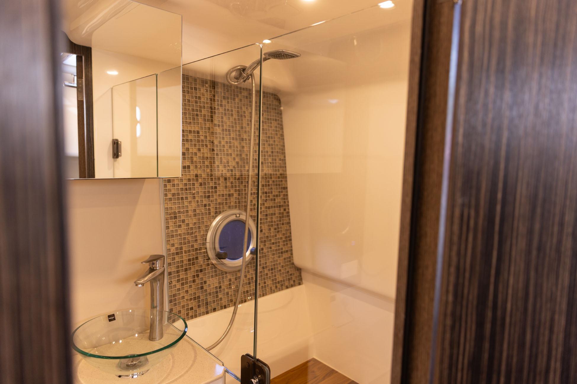 Modern bathroom in 2026 Hanover 387 with glass sink and mosaic tiles.