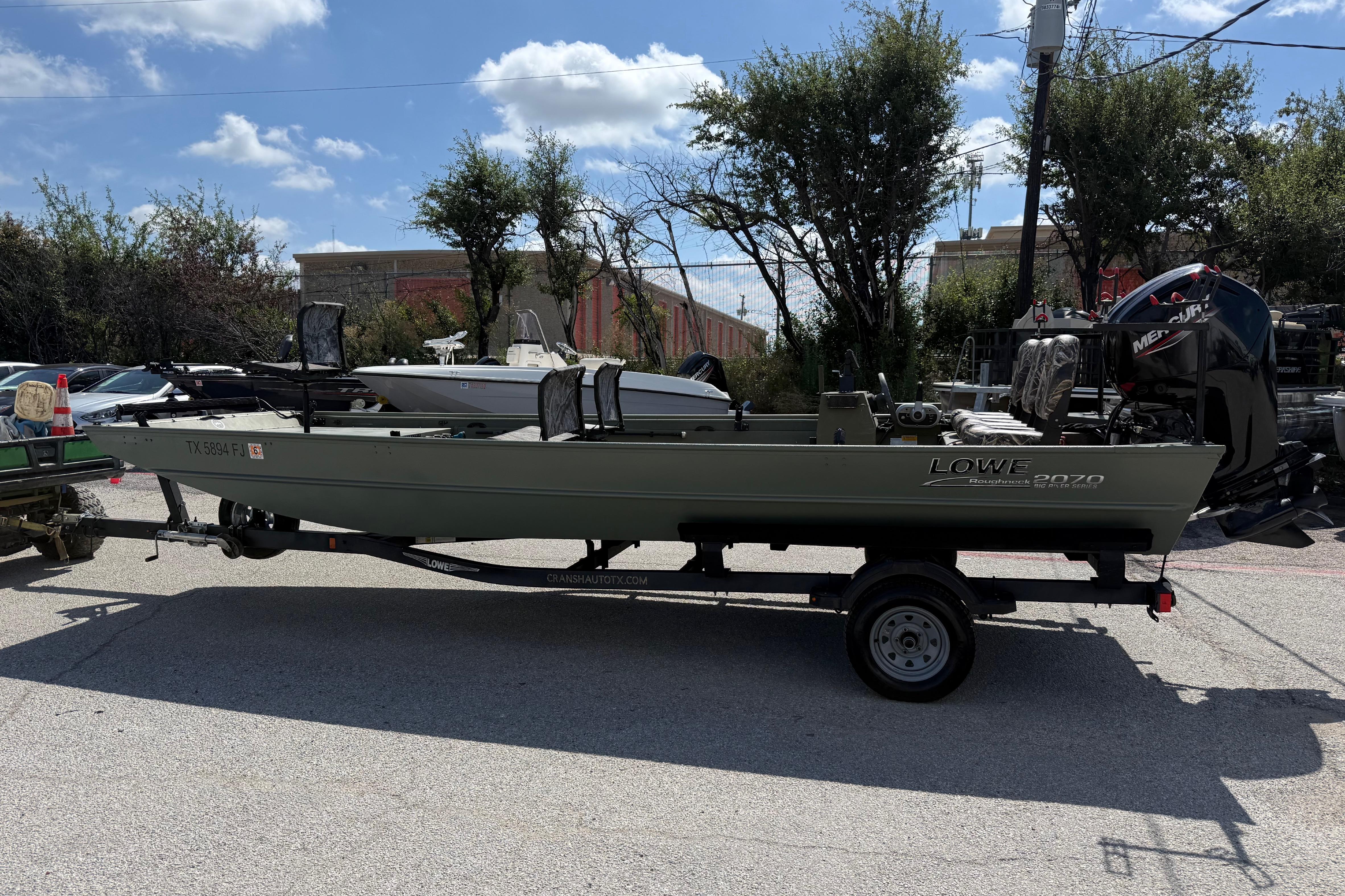 A 2020 Lowe Roughneck 2070 Big River boat on a trailer in a parking lot.
