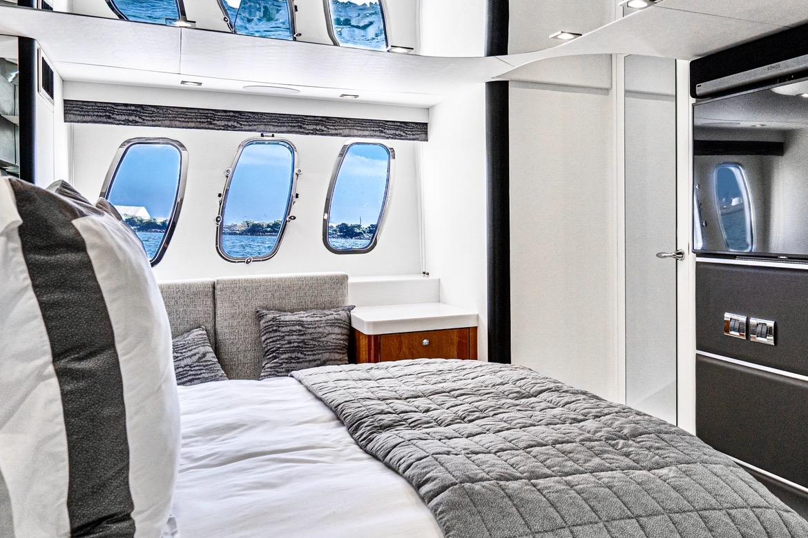 Luxurious bedroom interior of 2021 Sunseeker Predator 68 yacht with ocean view windows.