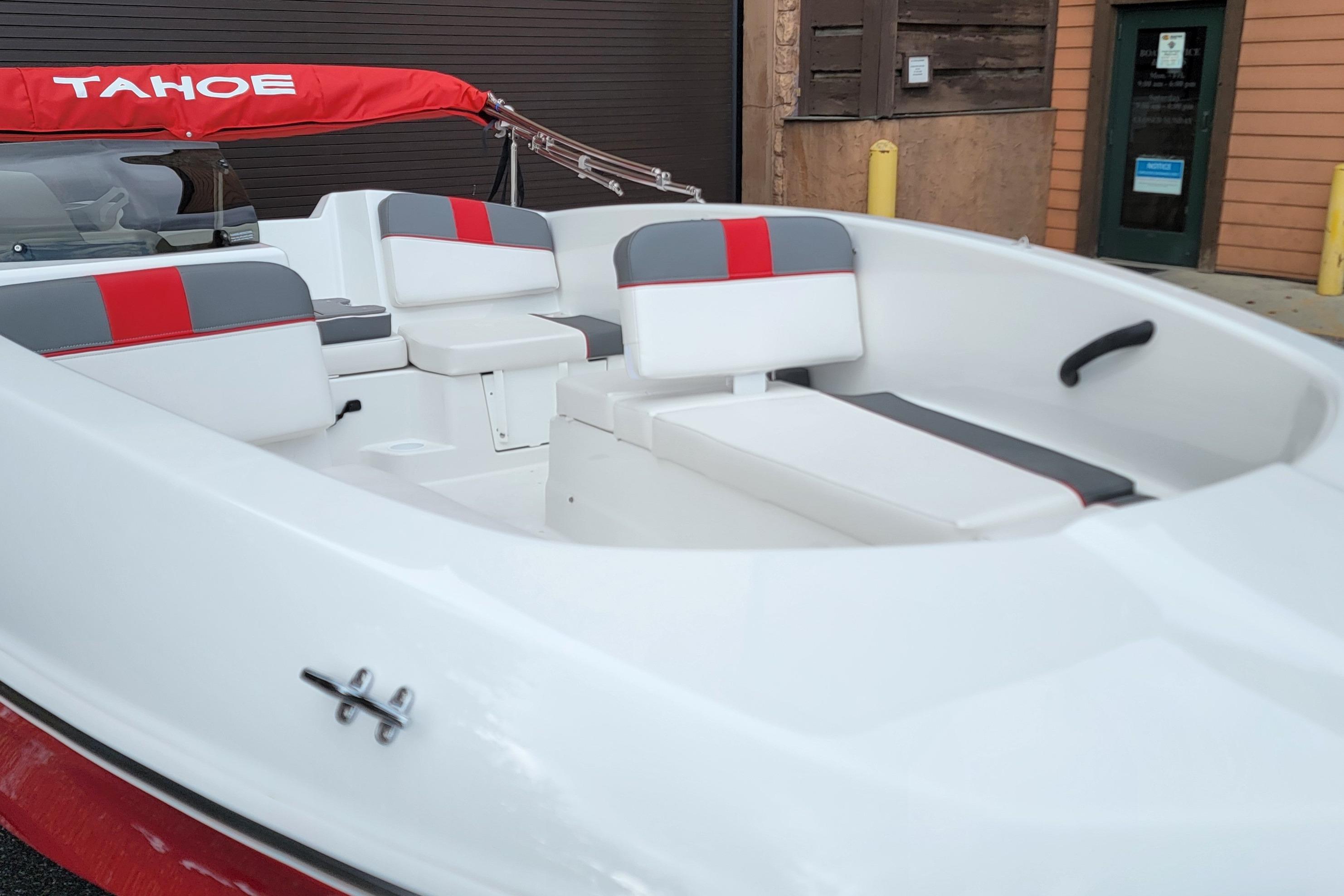 2026 Tahoe T16 boat interior with red and gray seating, docked near a building.