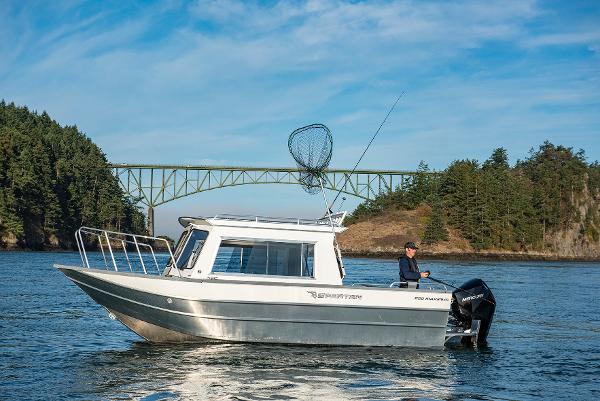 2023 Spartan 220 Maximus Pro boat on water with scenic bridge and forest background.