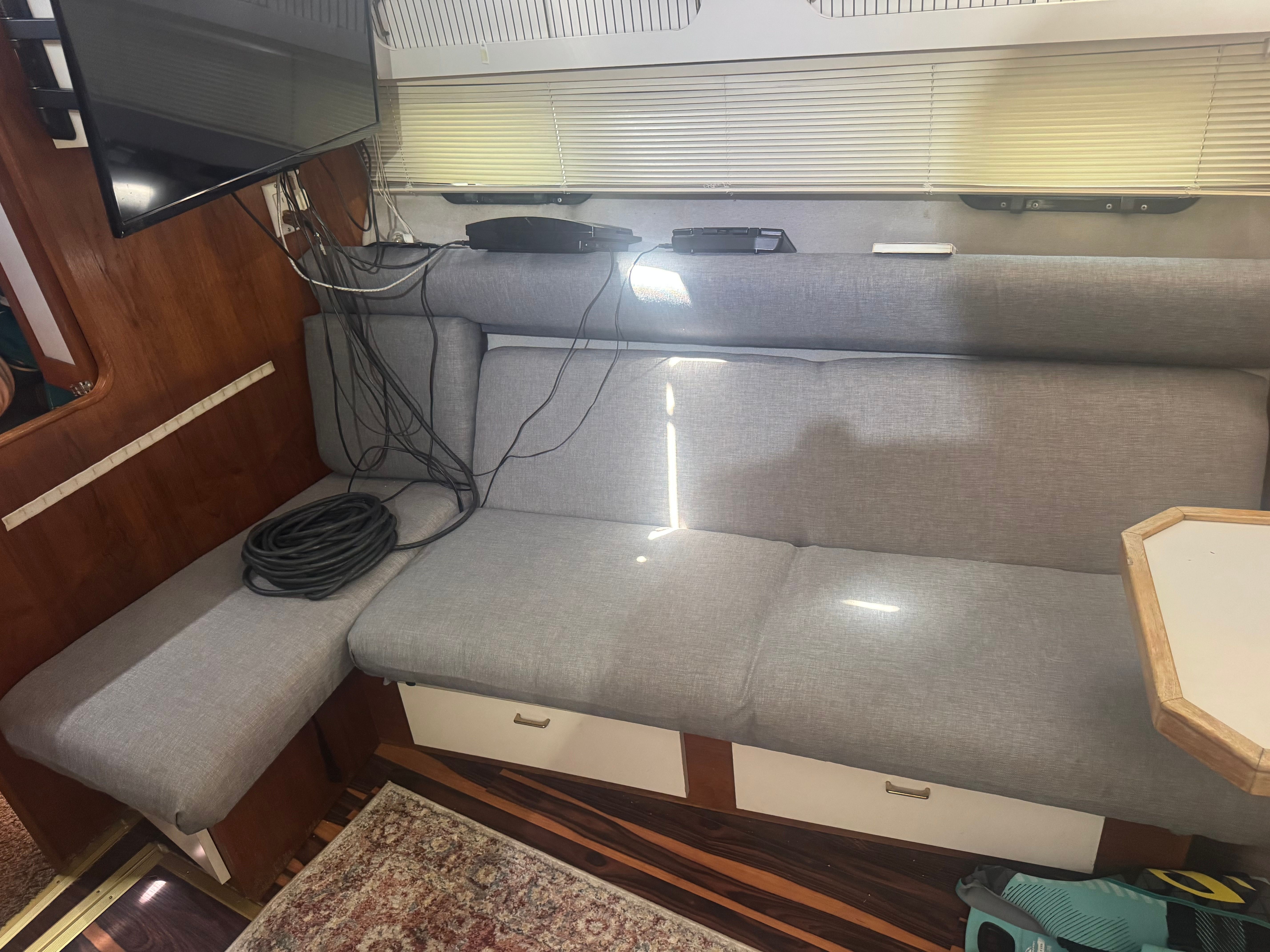 Interior of a 1992 Cruisers Yachts Esprit 3370 with a gray sofa and television.