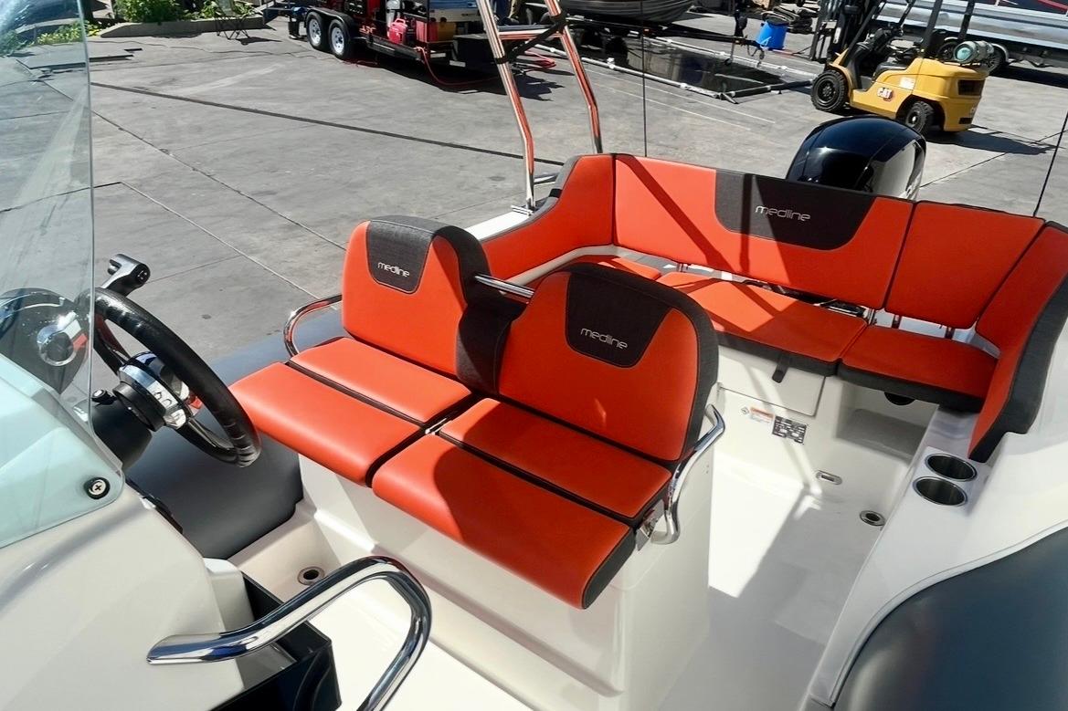 2024 Zodiac Medline 6.8 boat interior with vibrant orange seating and steering wheel.
