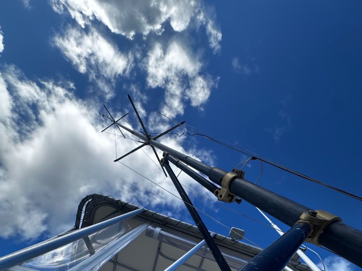 View of a boat's mast against a blue sky with clouds.