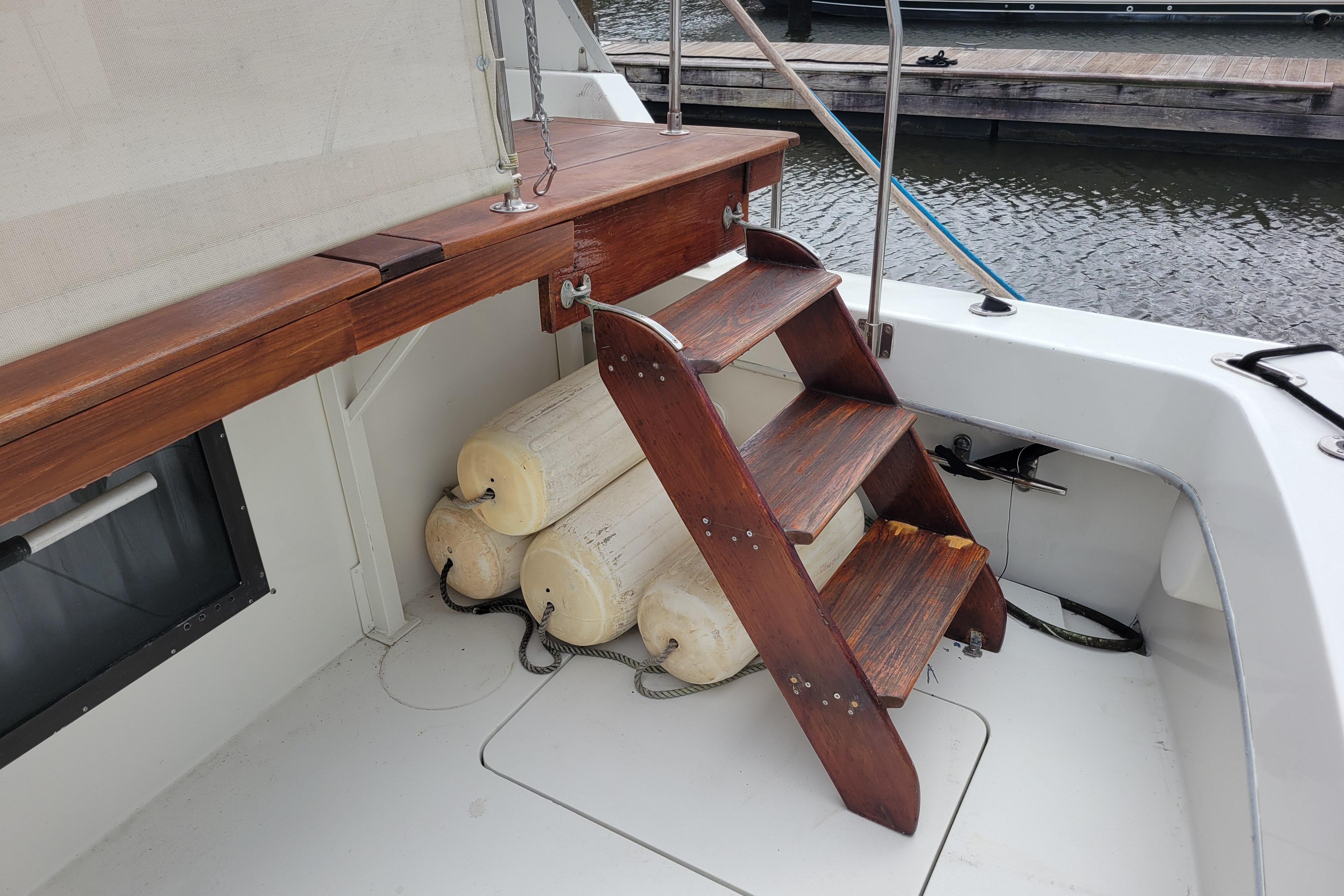 Wooden steps and fenders on 1980 Hatteras 53 Yacht Fisherman deck by the water.