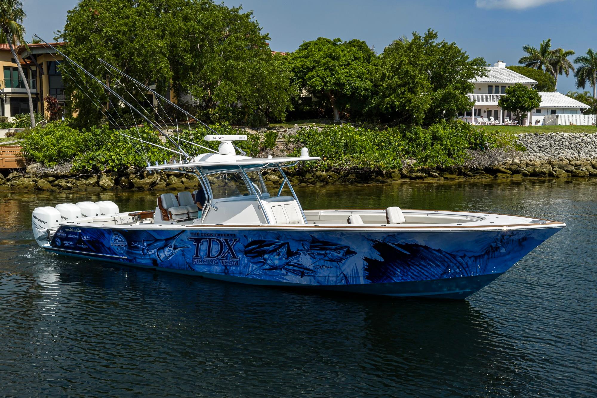 2020 Valhalla Boatworks V-41 with custom blue graphics, docked near lush greenery.