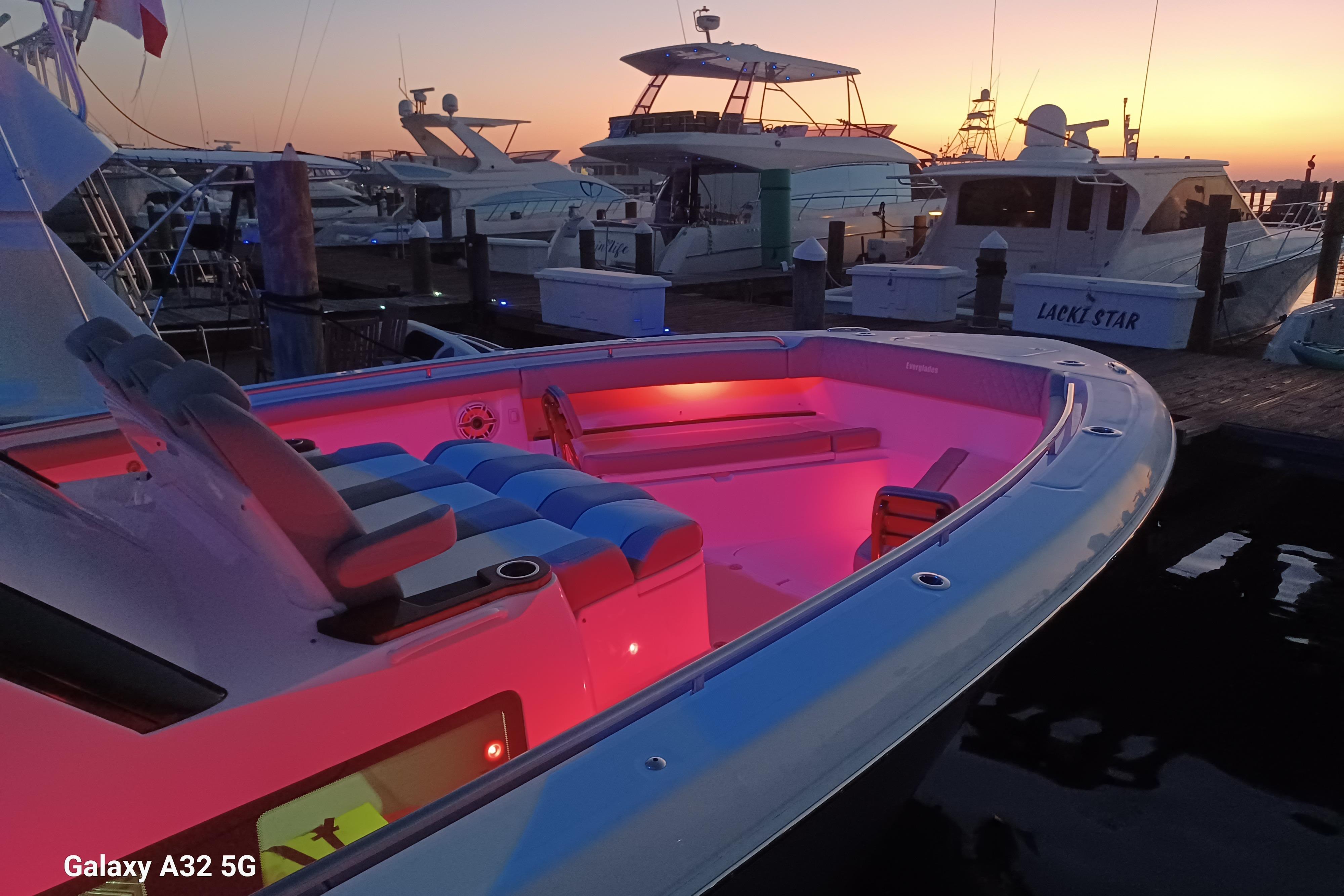 2024 Everglades 455 Center Console boat with pink interior lighting at sunset dock.