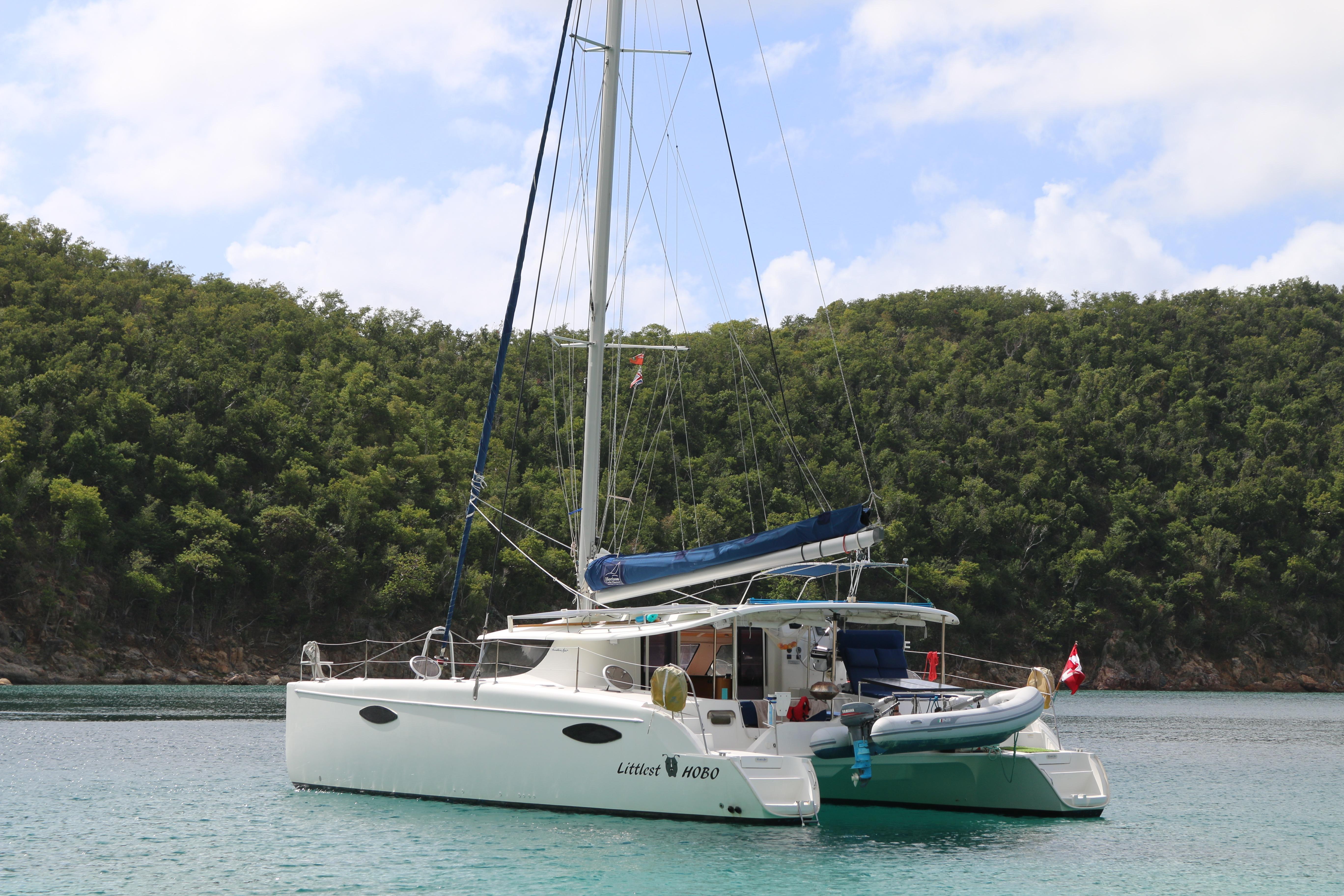 2009 Fountaine Pajot Orana 44 catamaran anchored in a serene bay with lush greenery.