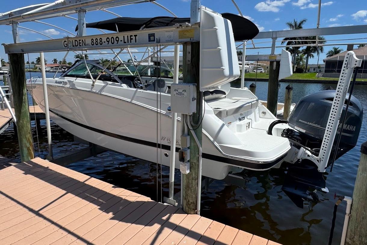 2020 Four Winns HD220 OB boat on lift by dock, sunny day, waterfront view.