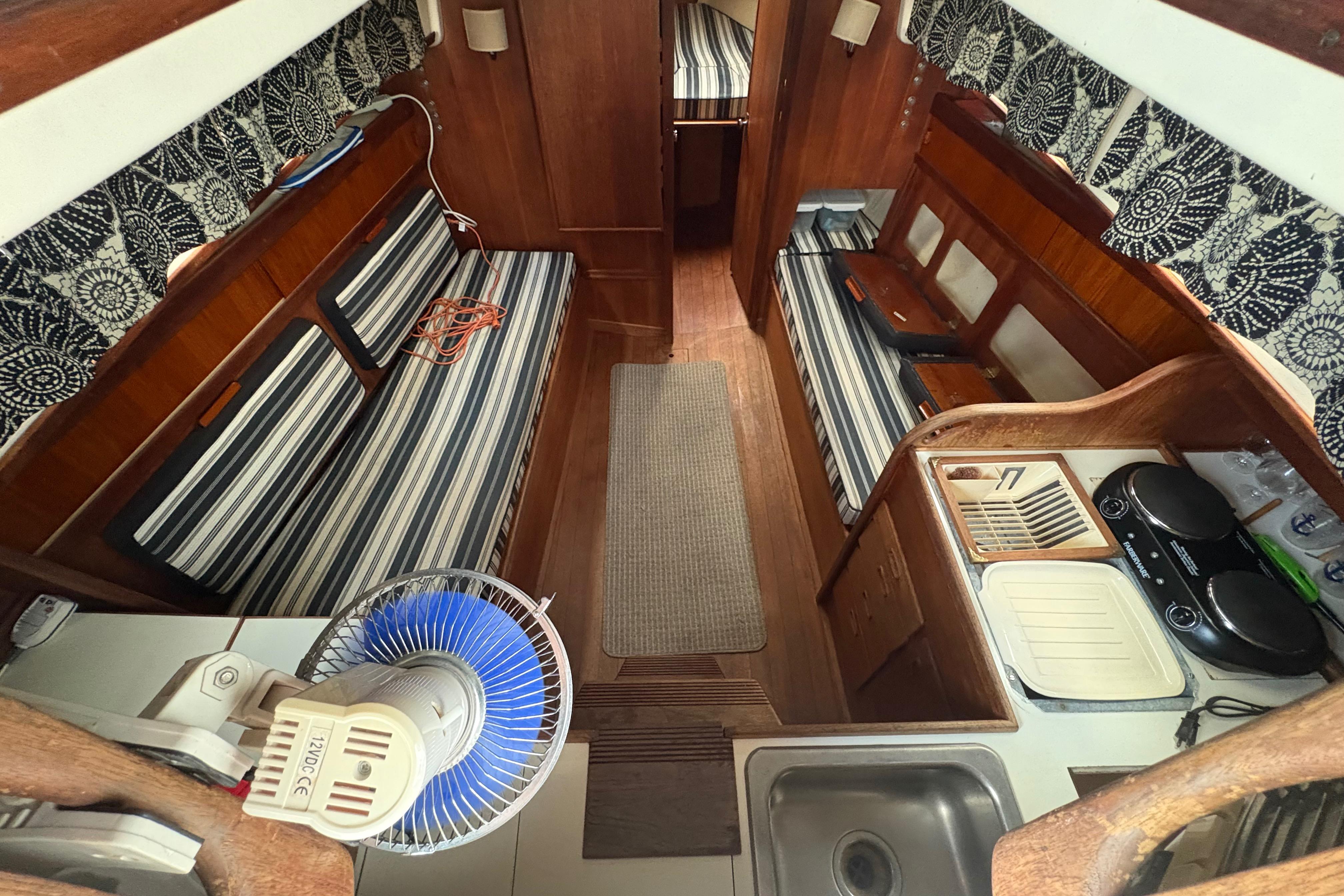 Interior of a 1981 Sabre 31 sailboat with striped seating and compact kitchen area.