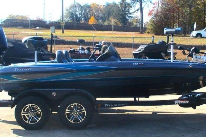 2026 Triton 18 TrX boat on trailer, parked outdoors, with trees in the background.