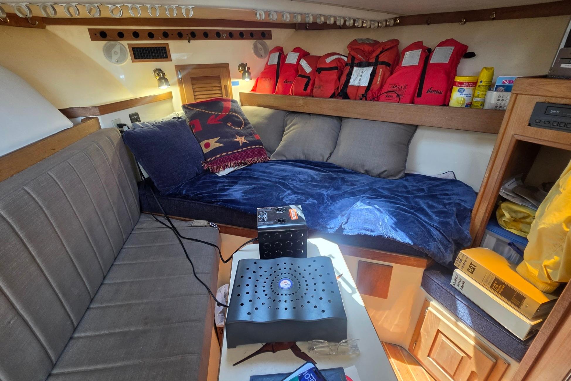 Cozy cabin interior of 1999 Albemarle 305 Express Fisherman with seating, cushions, and life jackets.