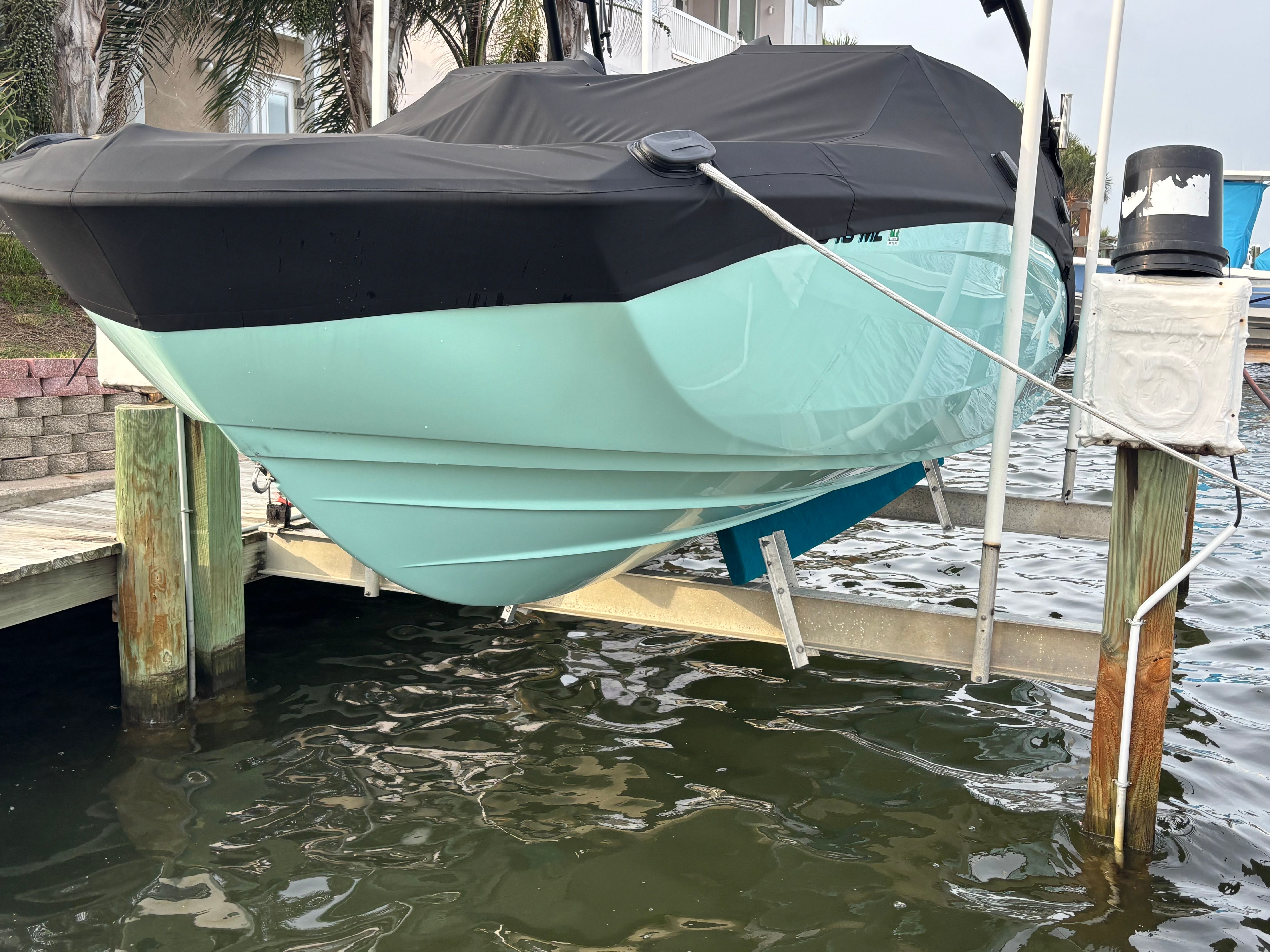 A 2024 Yamaha AR250 boat is on a lift above the water. It is covered.