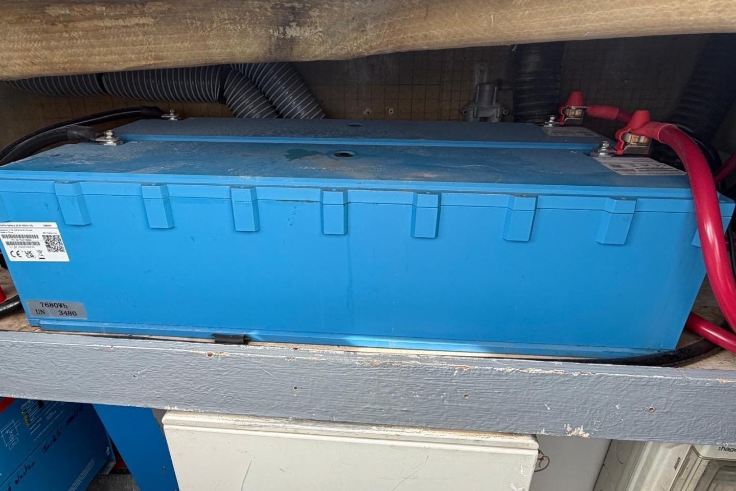 Blue battery in a 2013 Fountaine Pajot Sanya 57 yacht, connected with red cables.