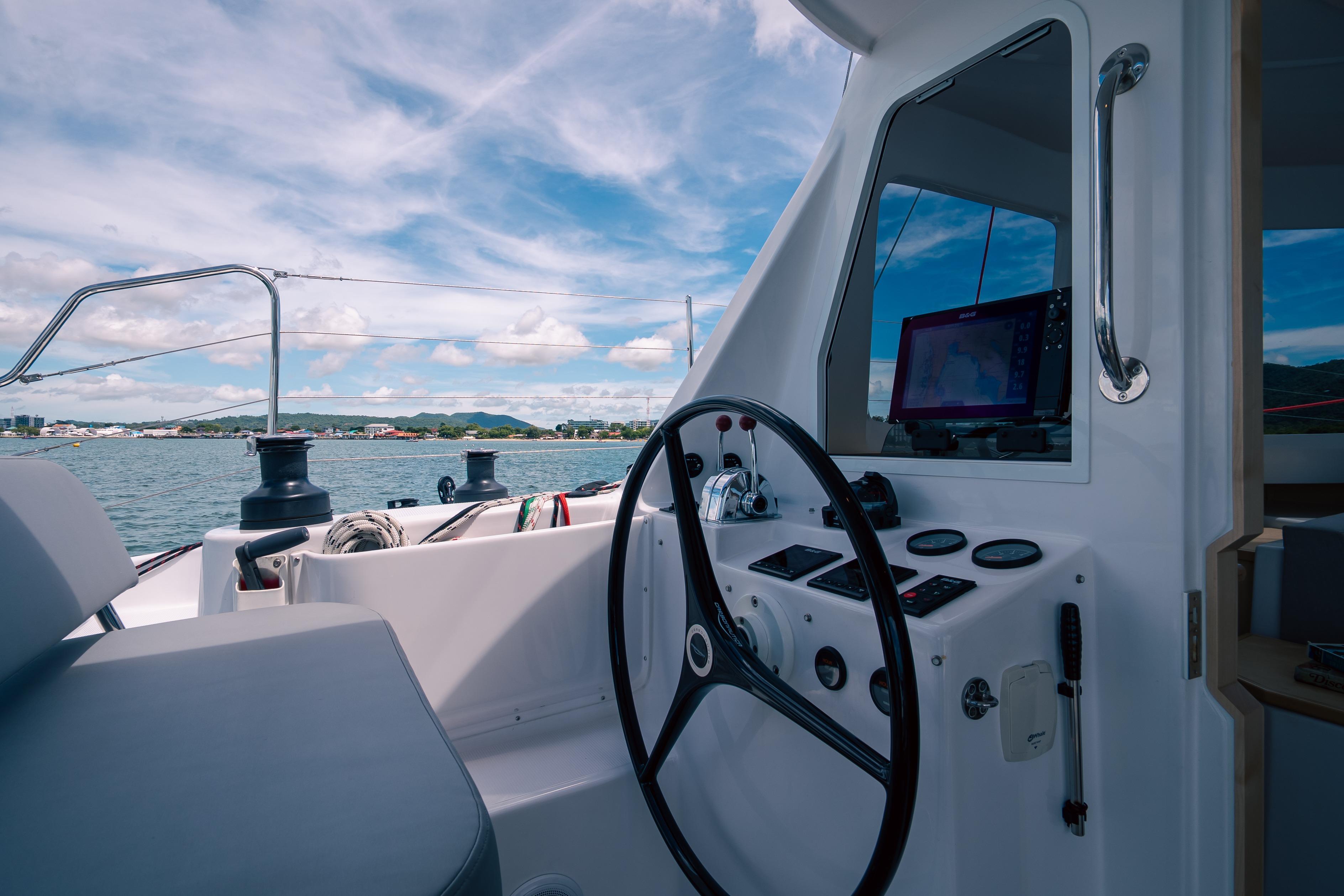2026 Seawind 1160XL yacht cockpit with steering wheel and navigation equipment, overlooking scenic waters.