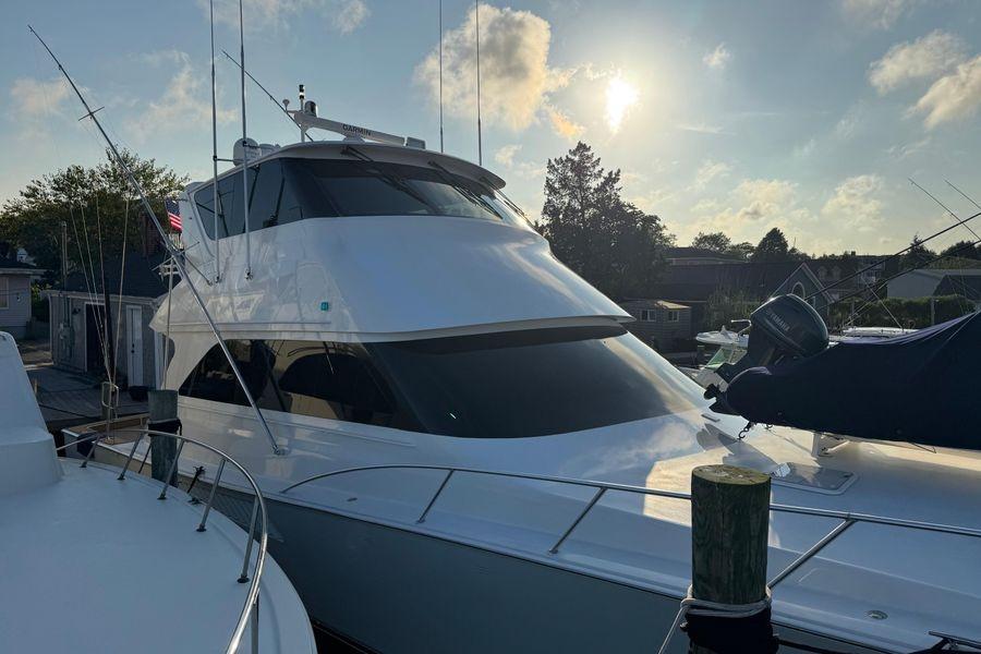 2002 Viking 61 Enclosed Bridge yacht docked at sunset, showcasing sleek design.