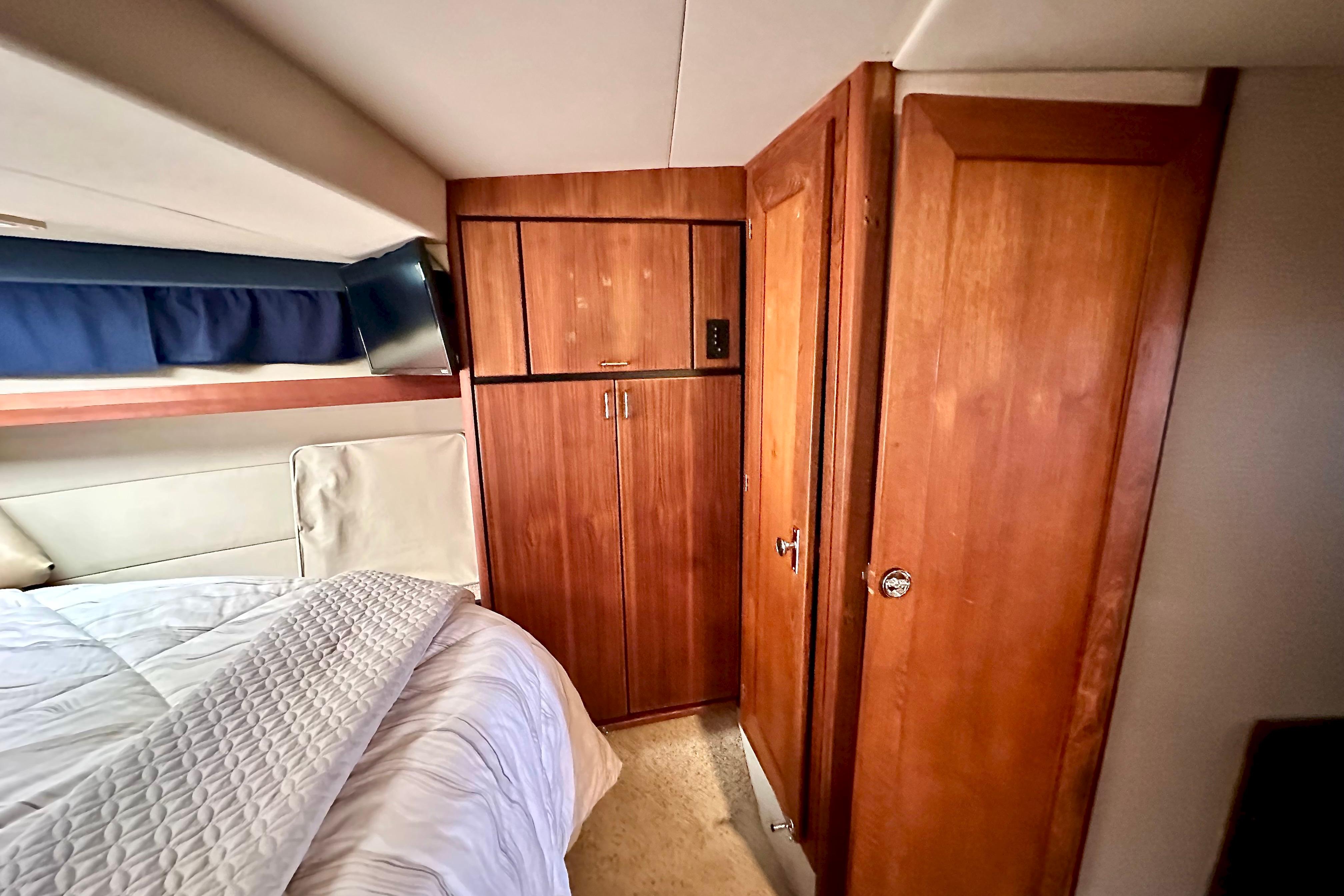 Interior cabin of 1993 Bayliner 4588 Pilothouse with wood cabinetry and cozy bedding.