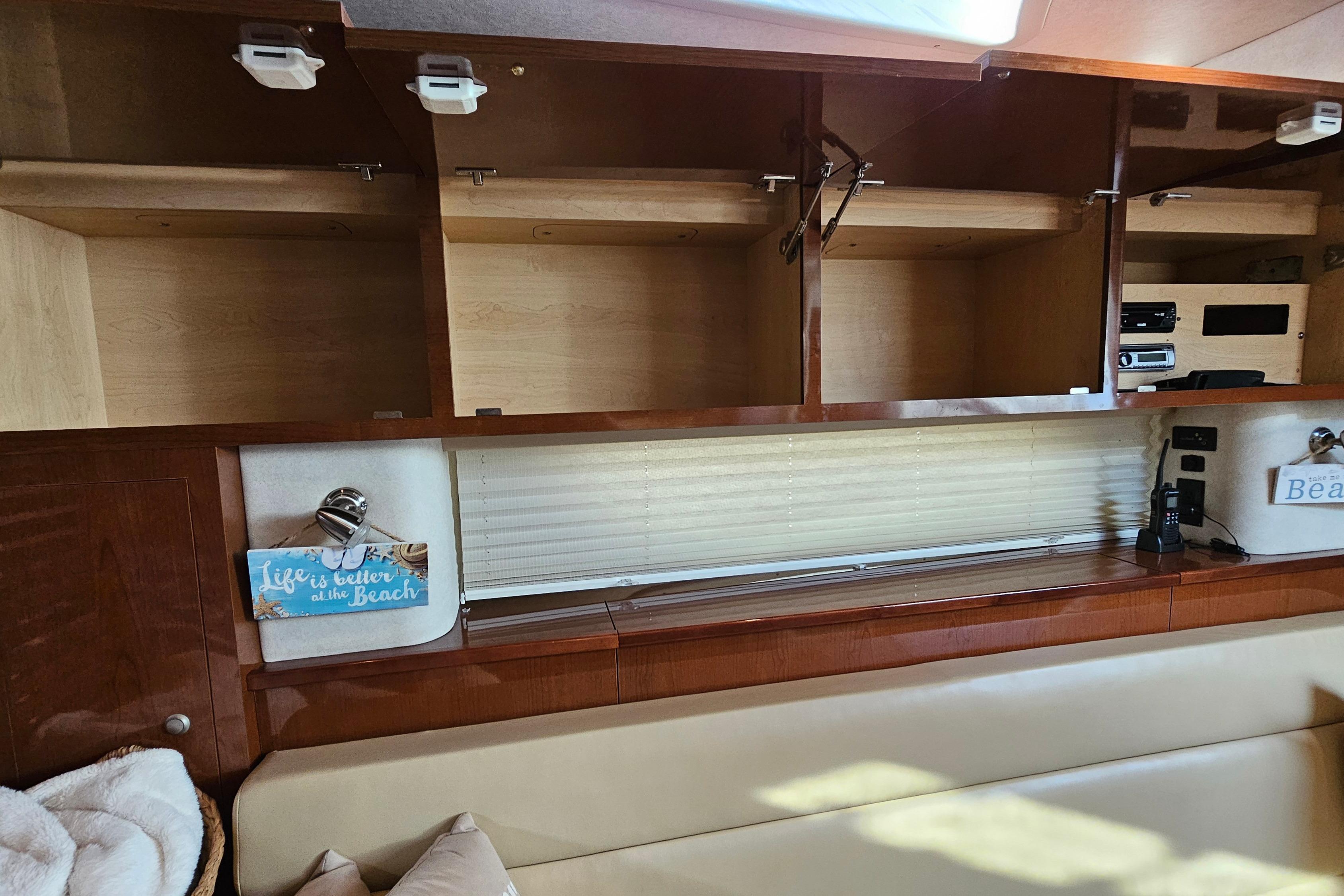 2008 Sea Ray Sundancer 350 interior with open cabinets and beach-themed decor.