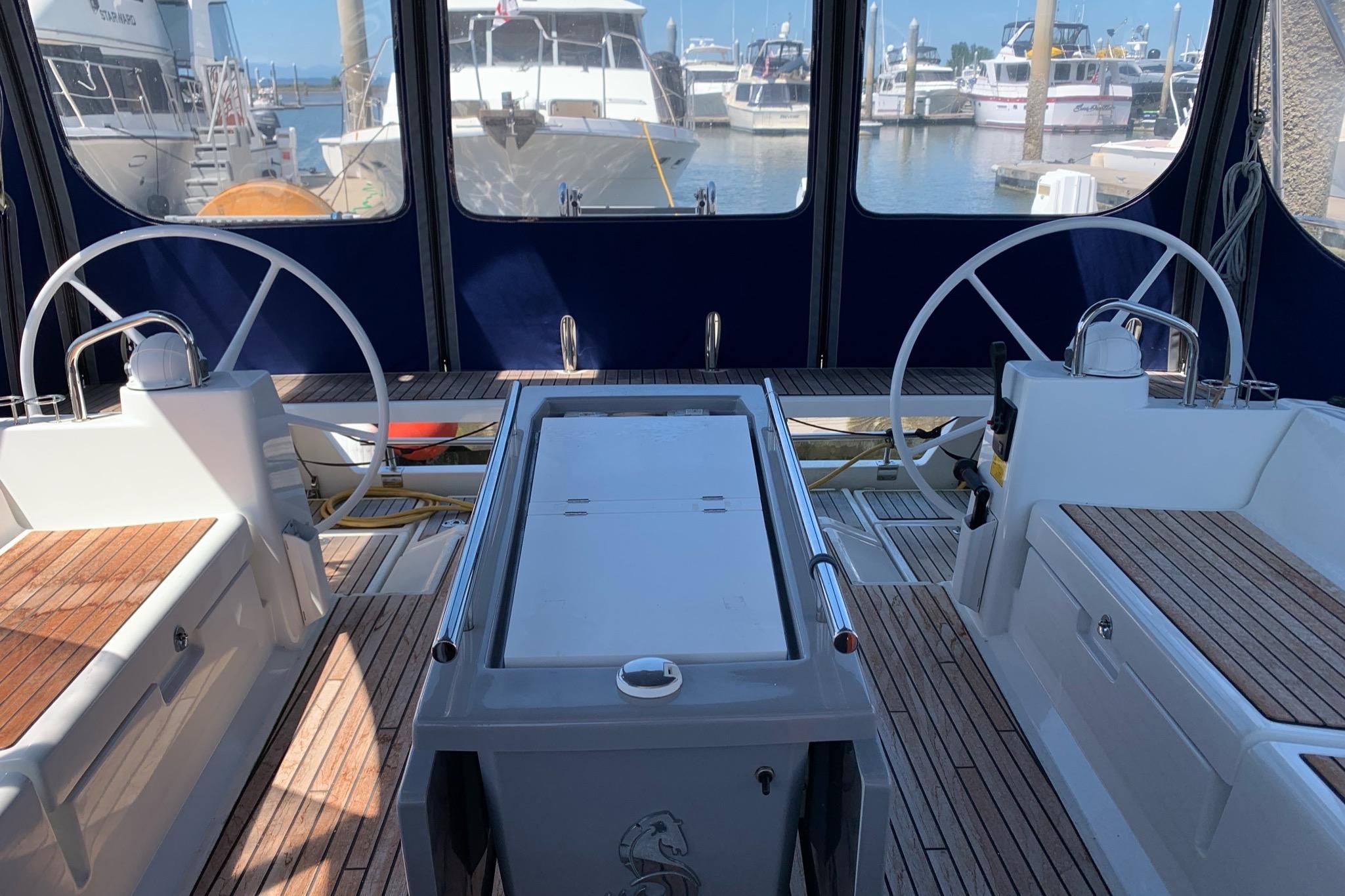 Cockpit of 2018 Beneteau Oceanis 45 yacht with dual steering wheels in marina.