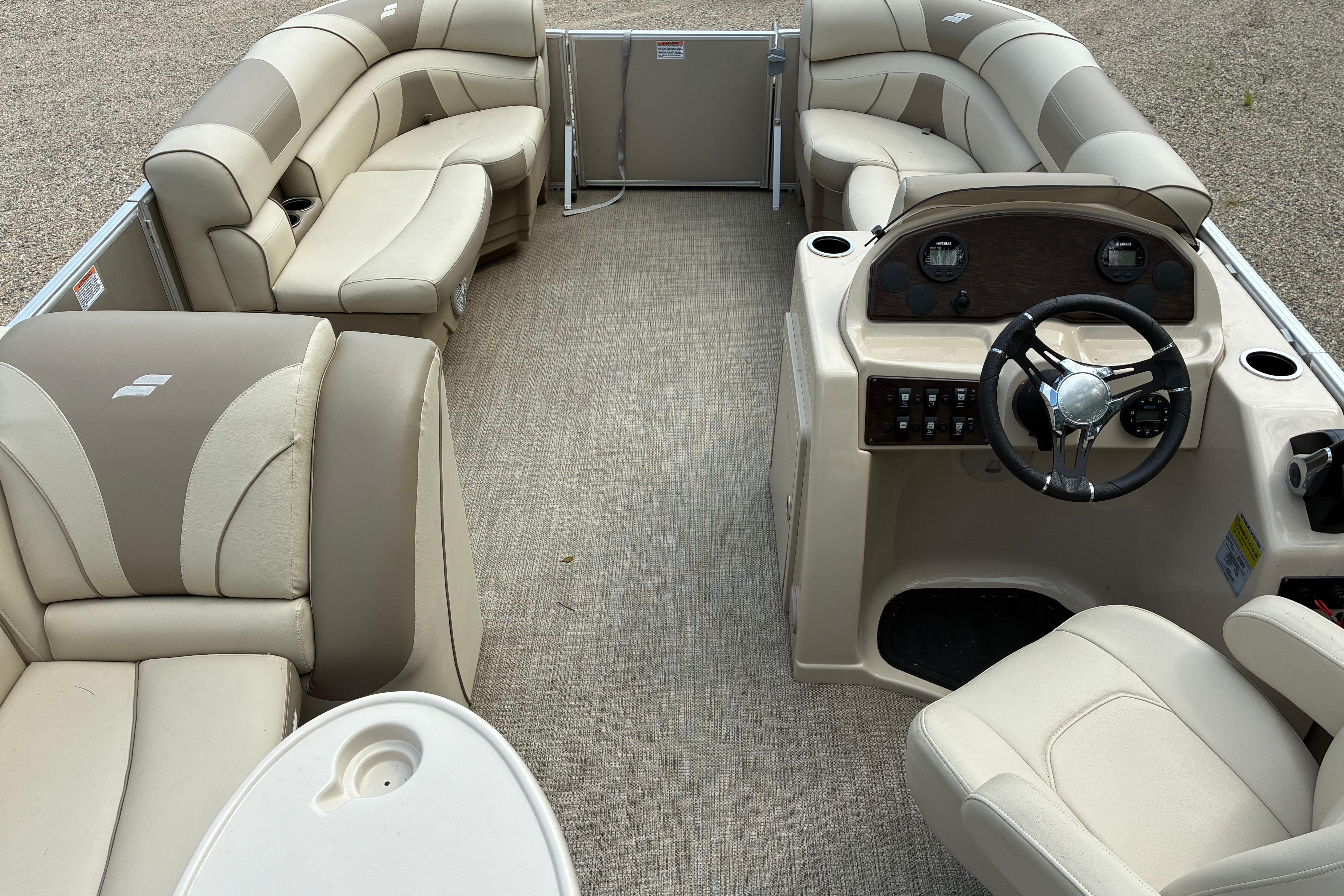 Interior of 2020 Starcraft EX 20 C pontoon boat with beige seating and steering console.