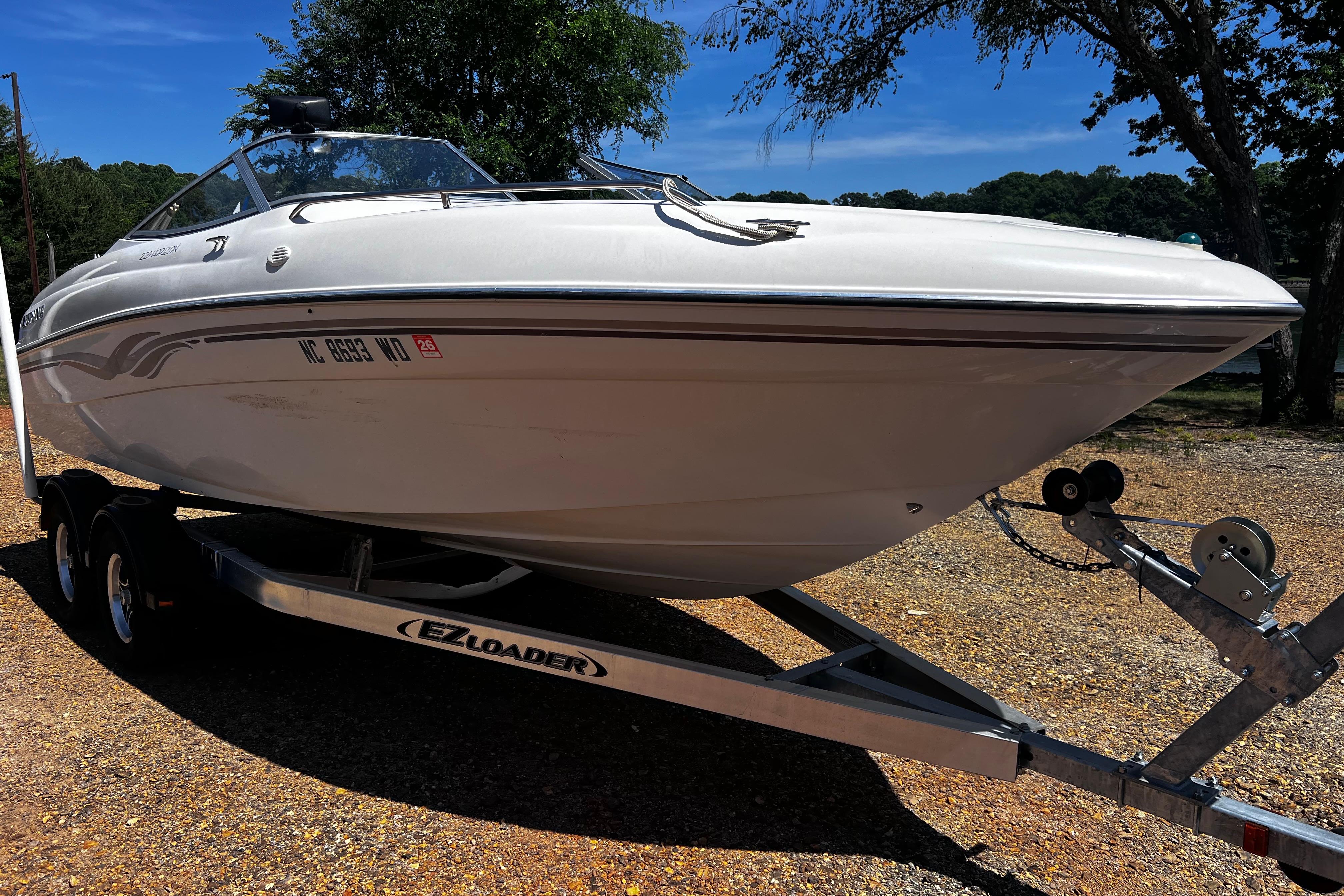 1998 Four Winns 220 Horizon boat on EZ Loader trailer, parked outdoors.