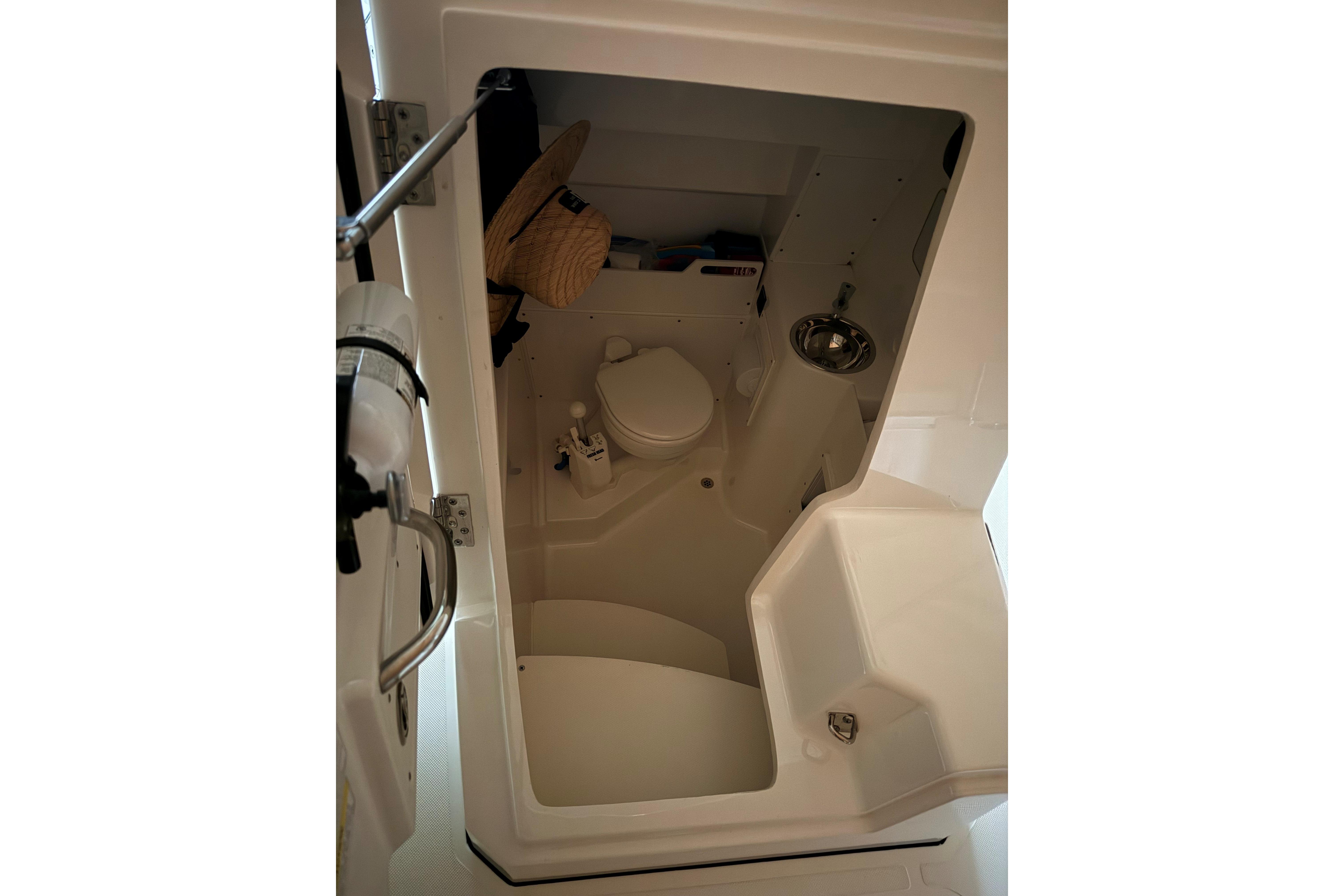 Interior of 2021 Pursuit S 268 Sport boat's compact bathroom with toilet and sink.