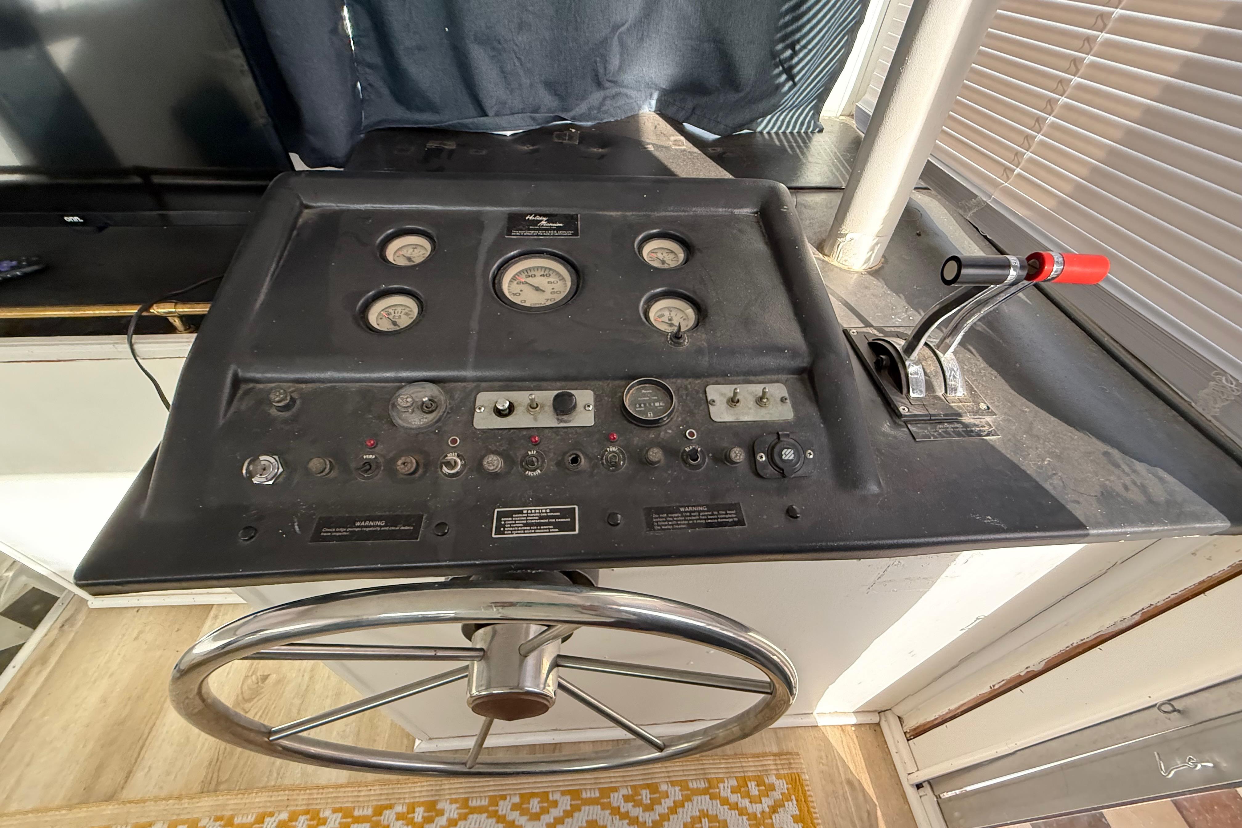 Control panel of a 1983 Holiday Mansion 37 Barracuda boat with gauges and steering wheel.