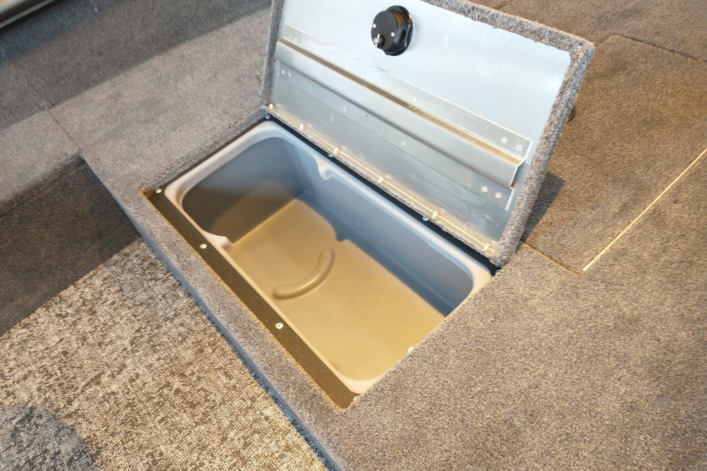 Open storage compartment in 2025 Tracker Super Guide V-16 T boat, featuring carpeted interior.