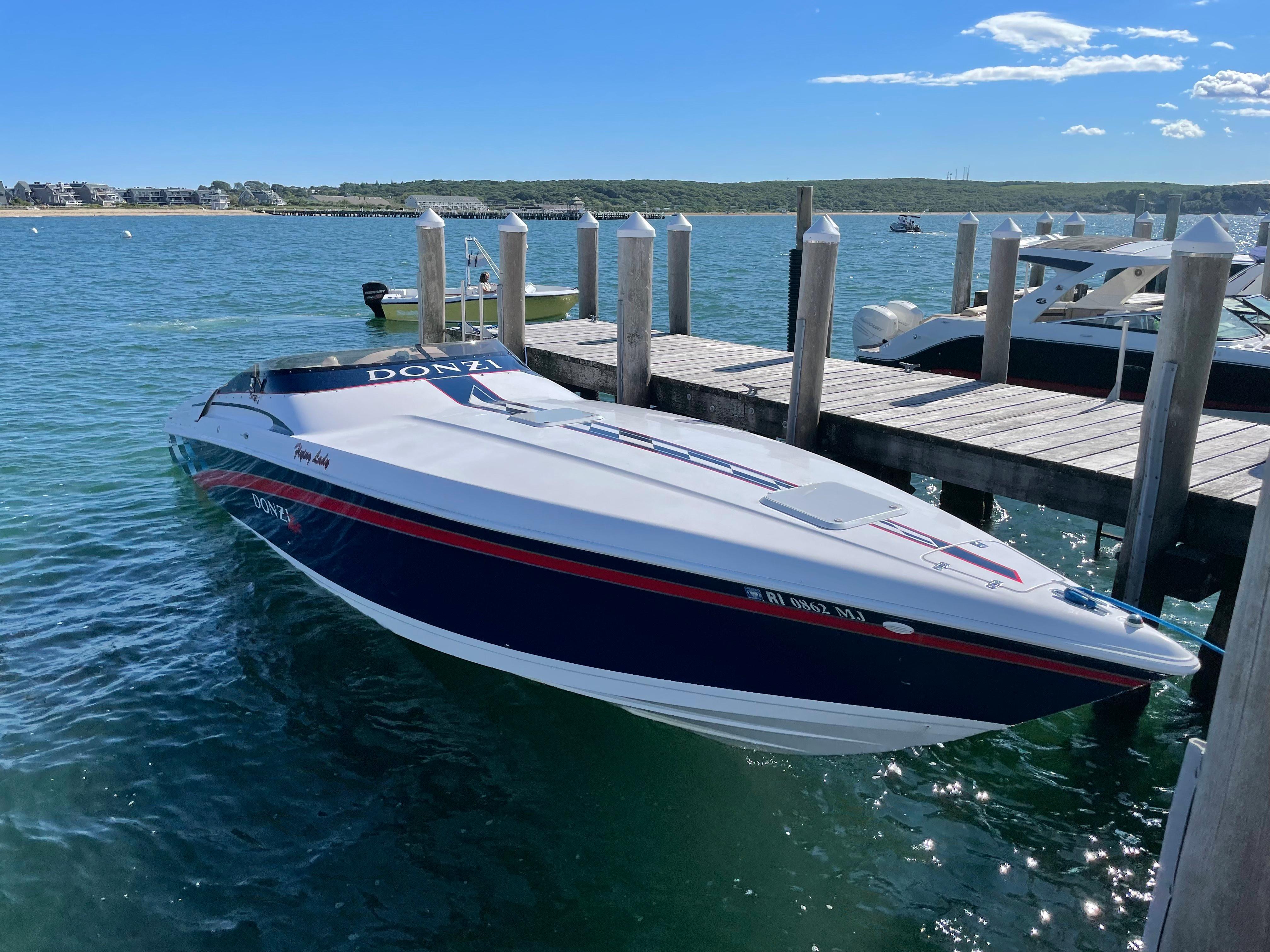 2001 Donzi 38 ZX speedboat docked on clear blue water under a sunny sky.