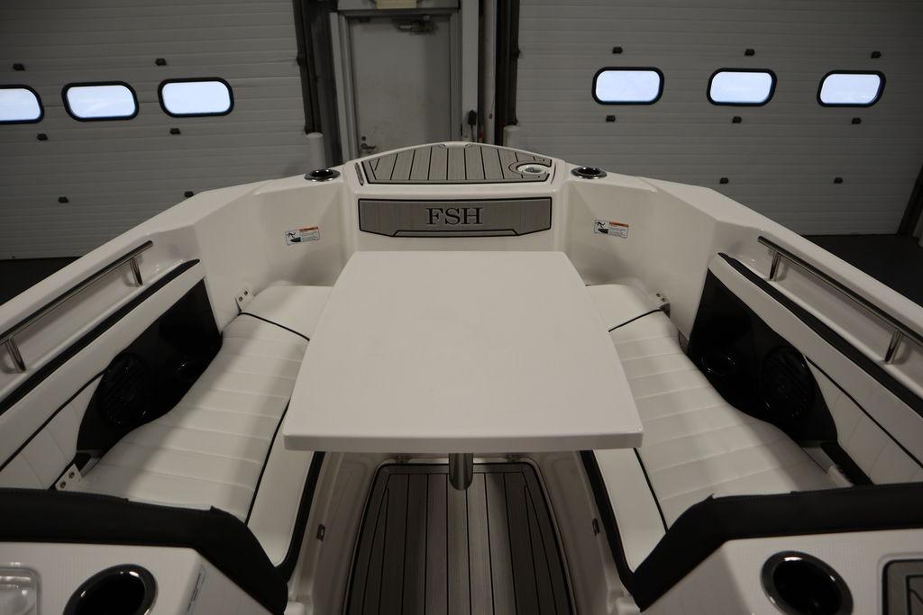 2026 Yamaha Boats 255 FSH Sport E interior with seating and table in a garage setting.