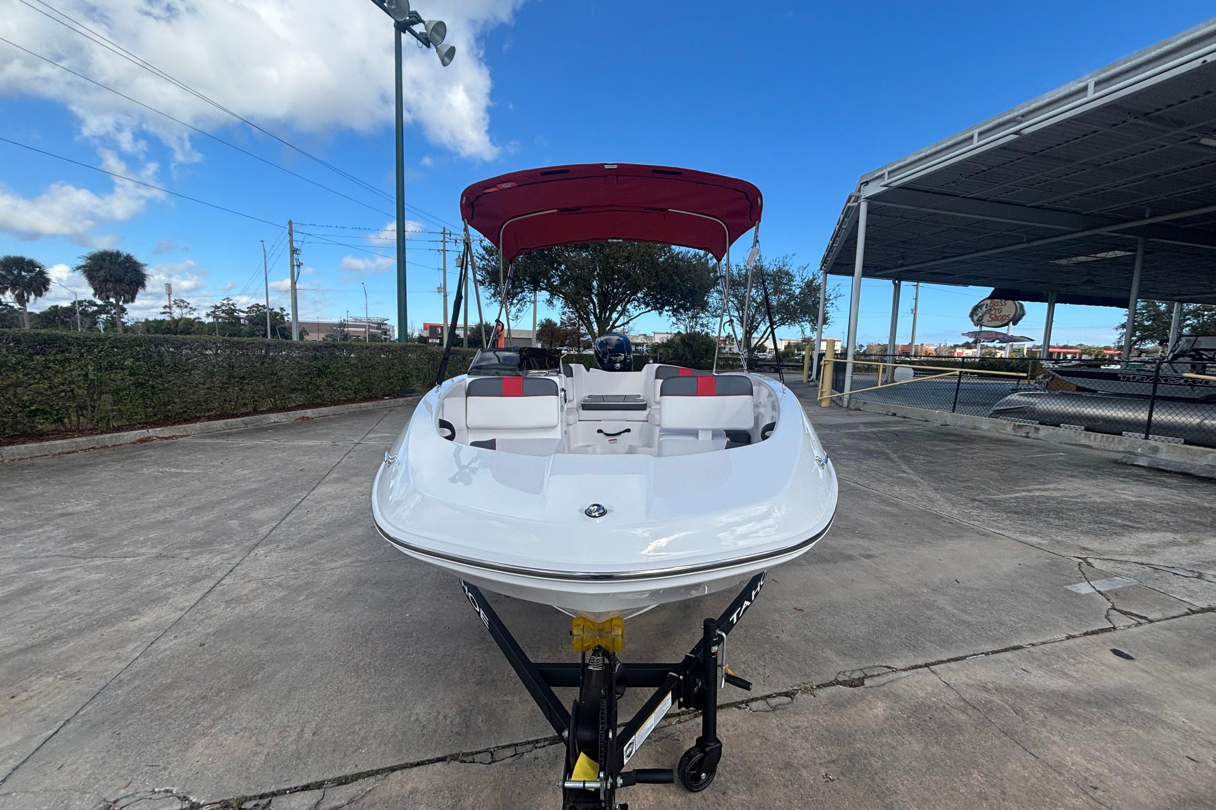 2026 Tahoe T16 boat with red canopy on trailer, parked outdoors under blue sky.