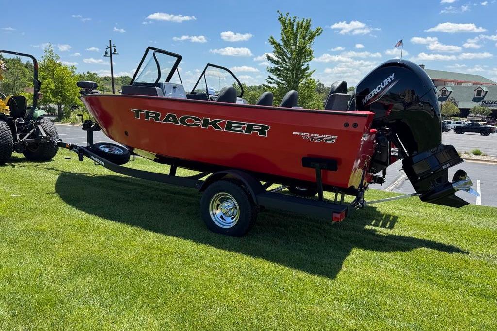 2026 Tracker Pro Guide V-16 WT boat on trailer, red exterior, parked on grass.