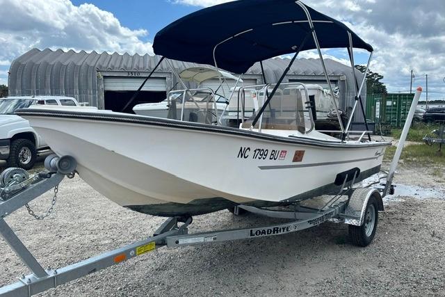 1989 Henry O 150 Dual Console boat on trailer with canopy, parked outdoors.