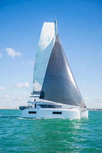 2025 Lagoon 38 catamaran sailing on turquoise waters under a clear blue sky.