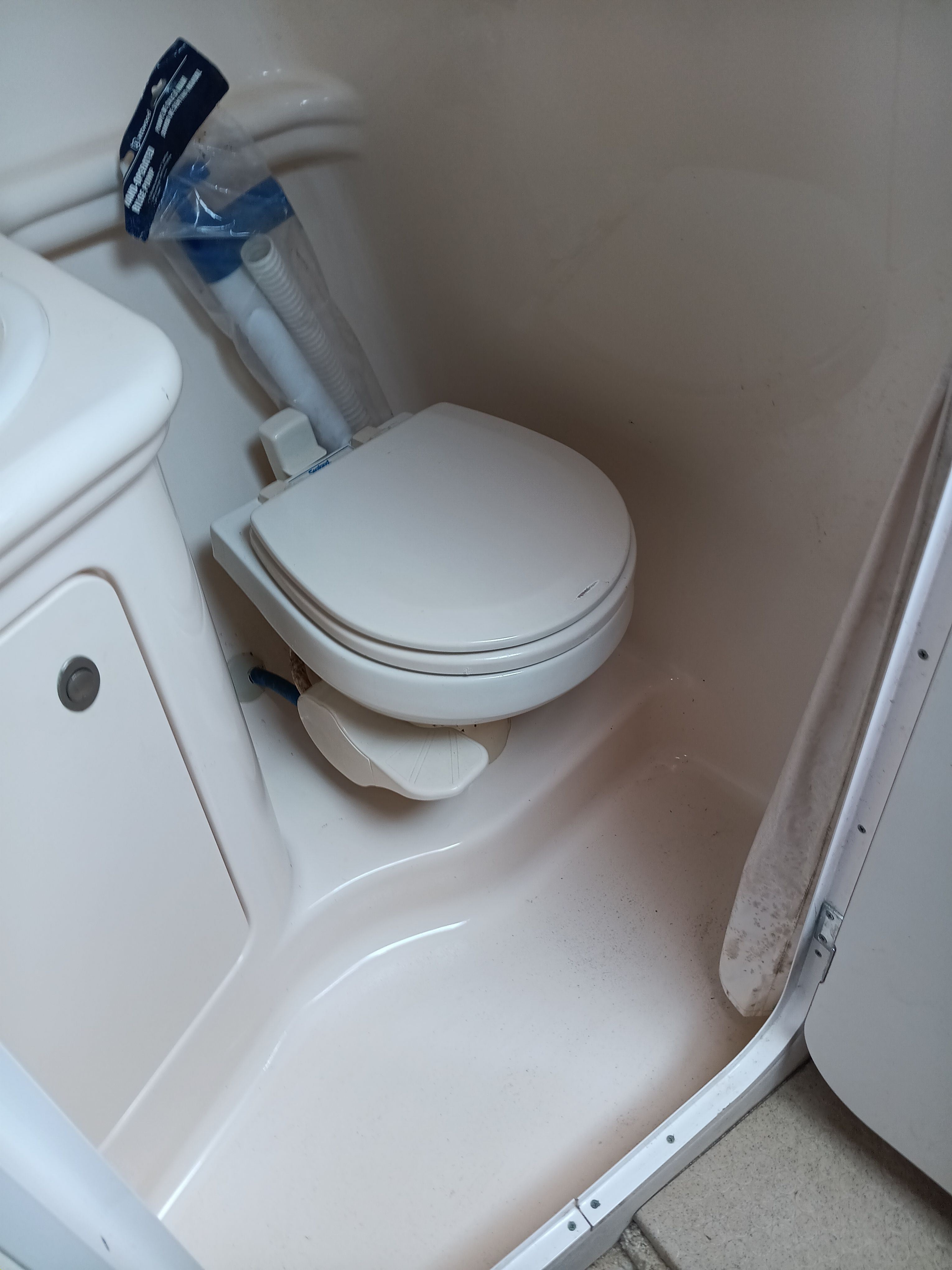 The image shows a compact boat toilet with white fixtures.