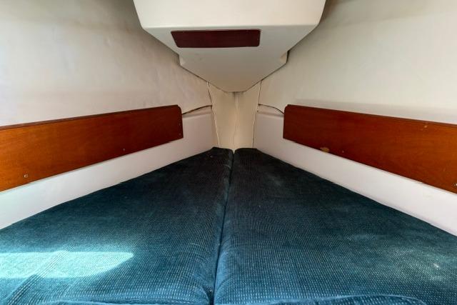 Interior cabin of 2000 Beneteau Oceanis 321 sailboat with blue cushions and wooden accents.