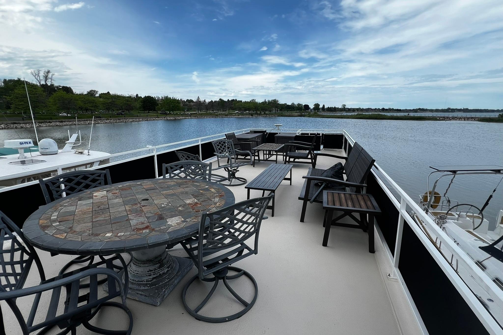 Flybridge deck of 2010 Skipperliner 480 with seating, overlooking serene water and lush shoreline.