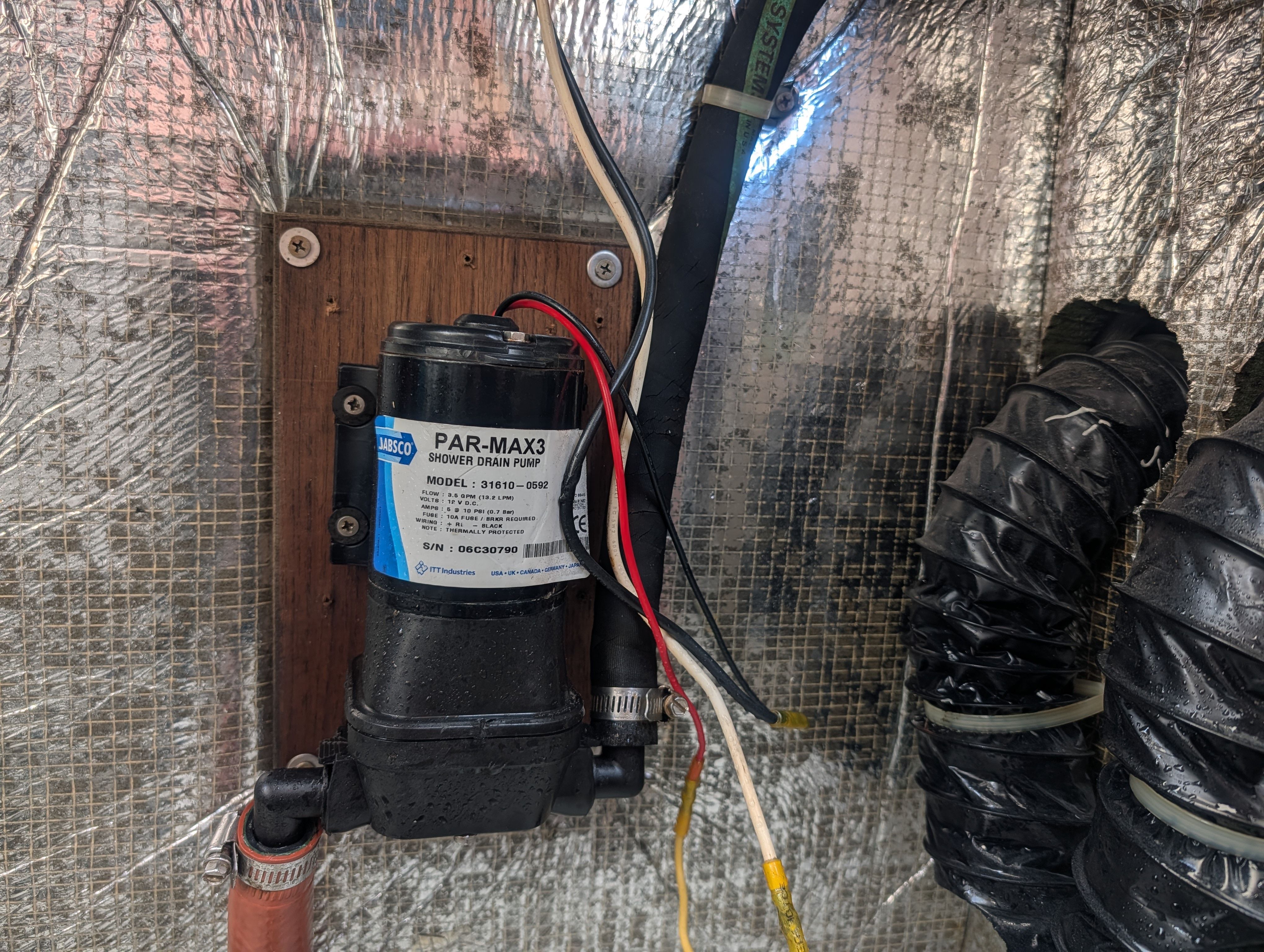 A pump in a boat's engine room, surrounded by insulation and wires.