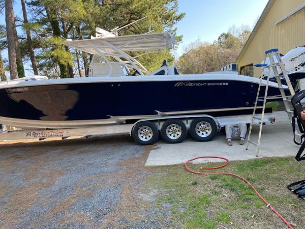 2019 Midnight Express 39 Cuddy boat on trailer, parked outdoors near trees and building.