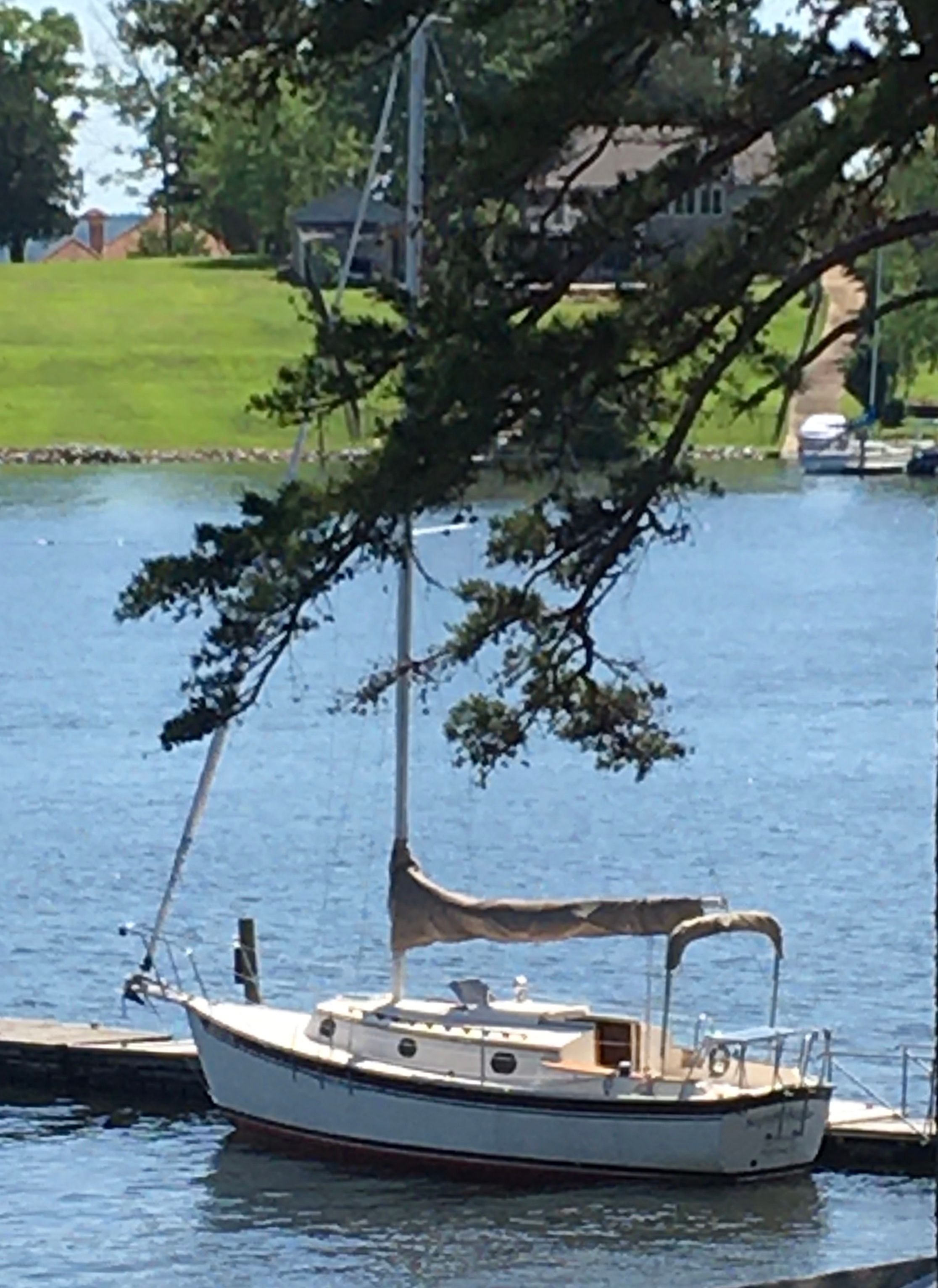 1988 Com-Pac 27 sailboat docked, surrounded by trees.