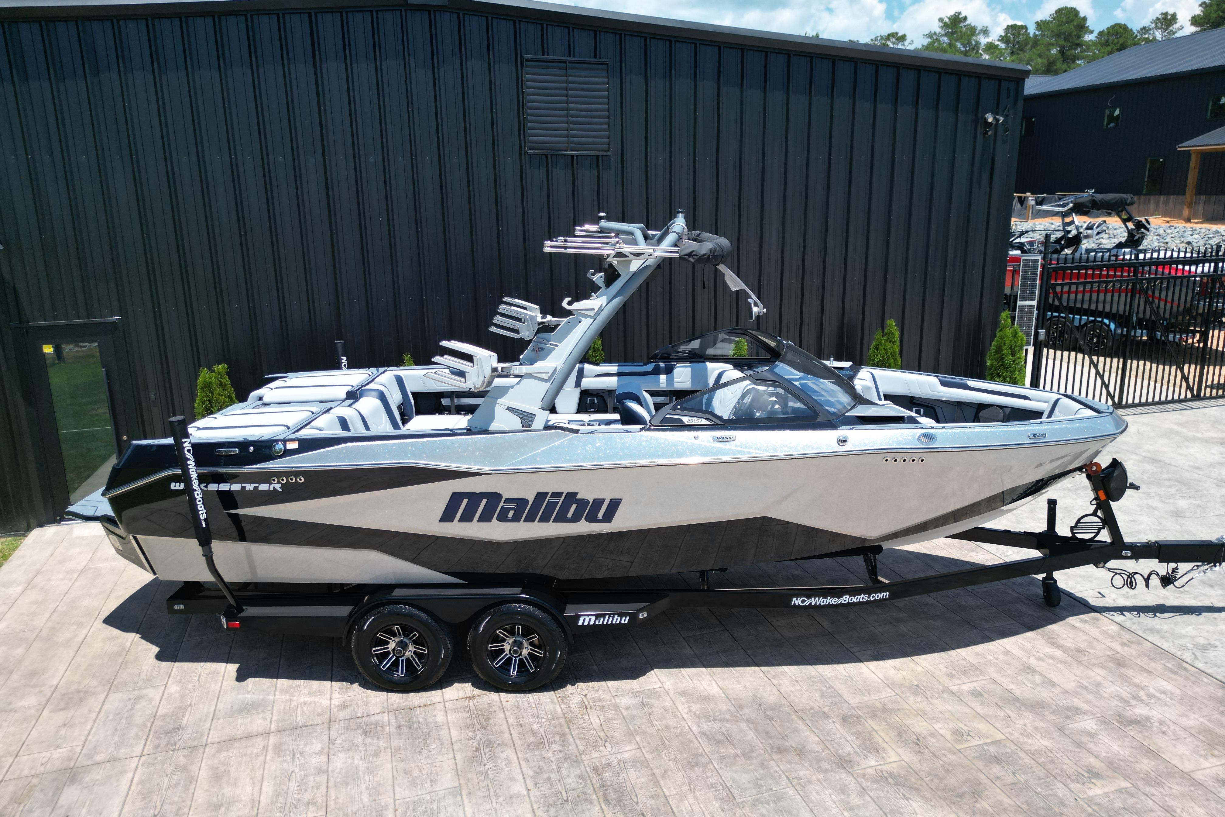 2025 Malibu Wakesetter 25 LSV boat on trailer, parked outside a black building.