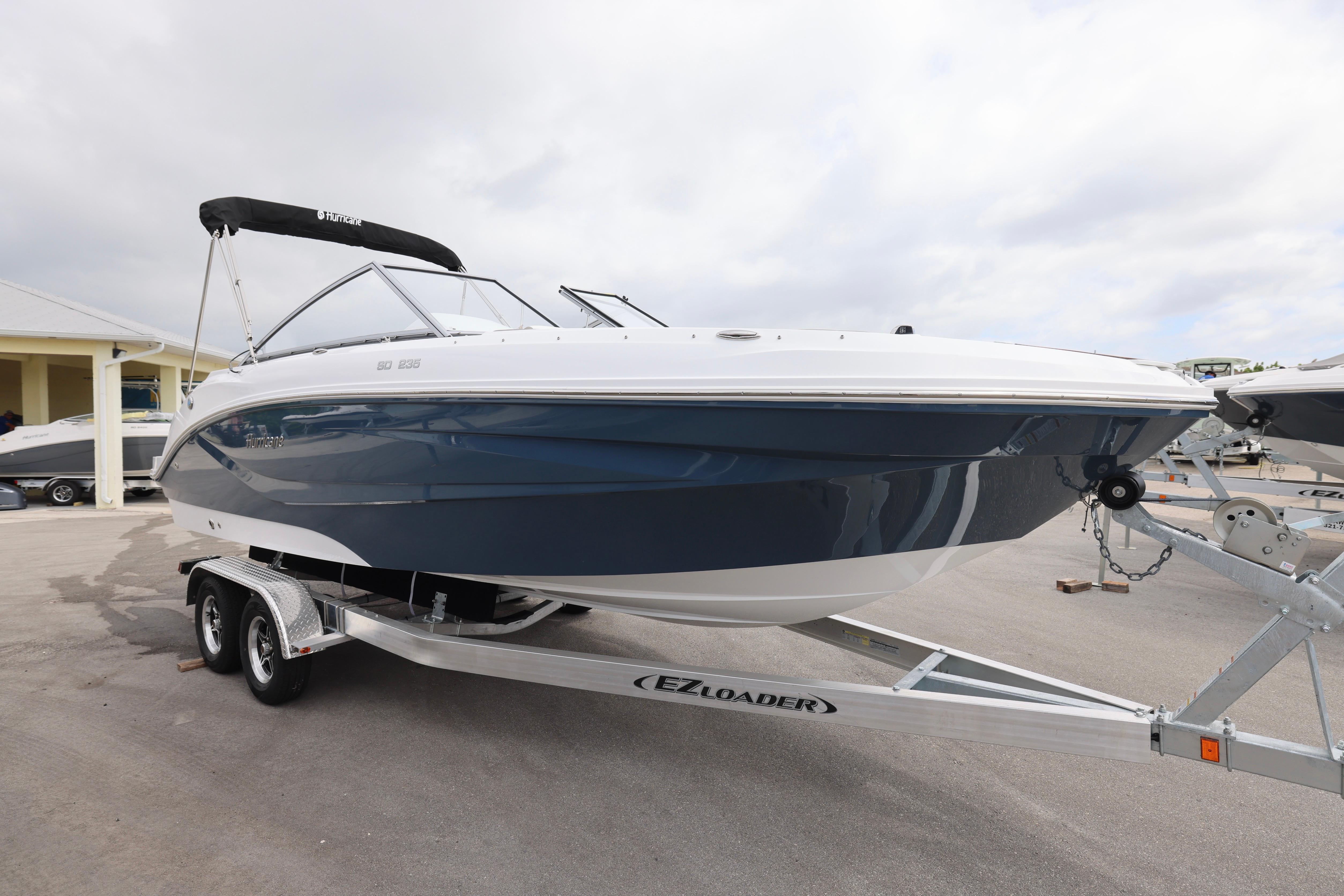 2026 Hurricane SunDeck 235 OB boat on trailer, sleek design, blue and white finish.