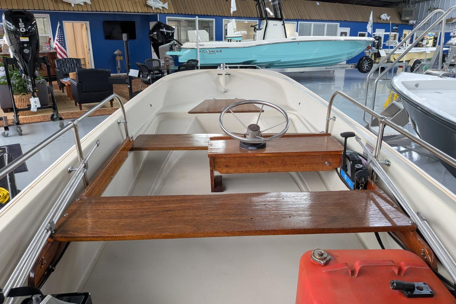 1978 Boston Whaler 15 SPORT boat interior with wooden seats and steering wheel in showroom.