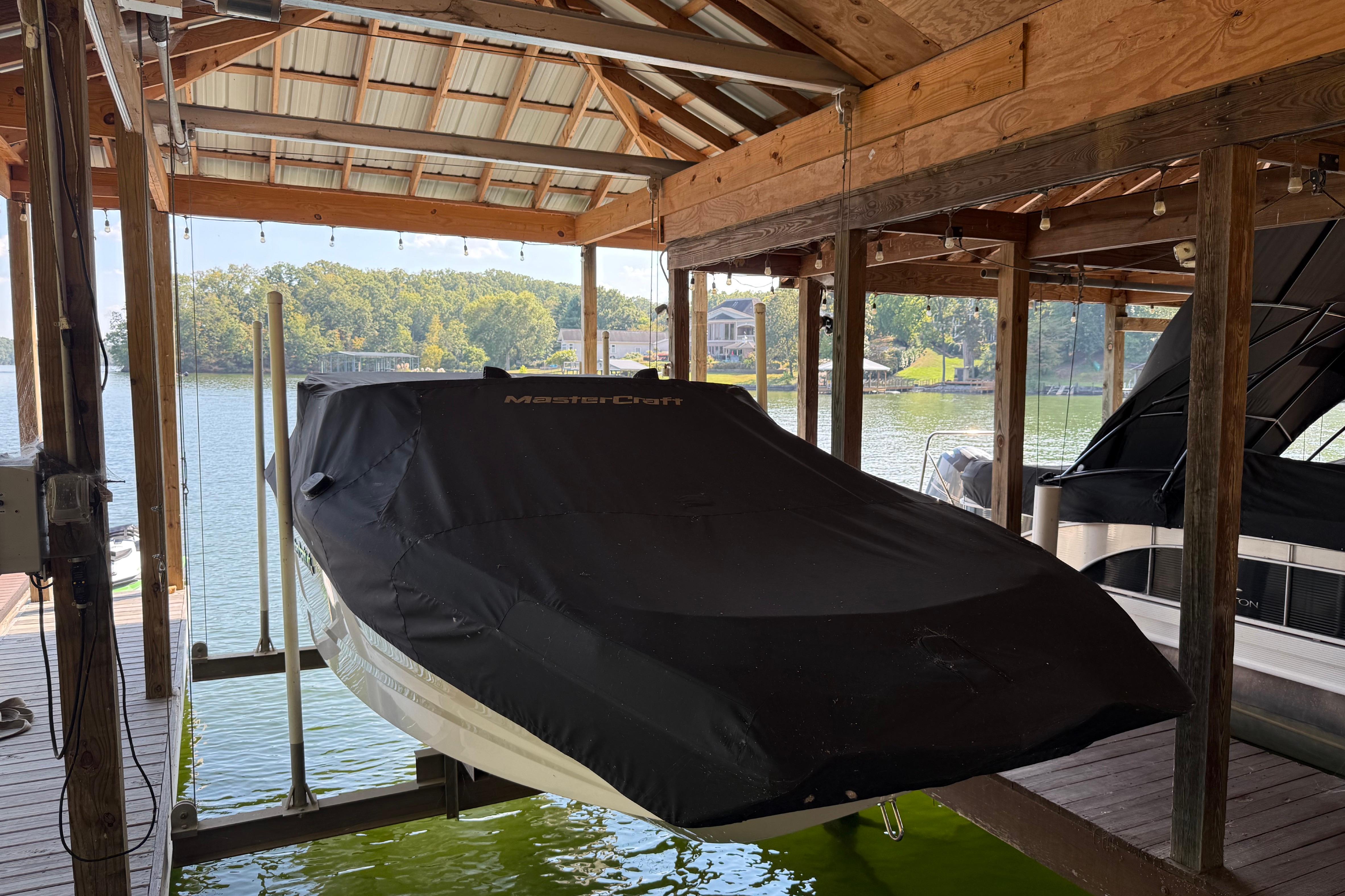 2022 MasterCraft NXT24 boat covered in a dock, surrounded by a scenic lake view.