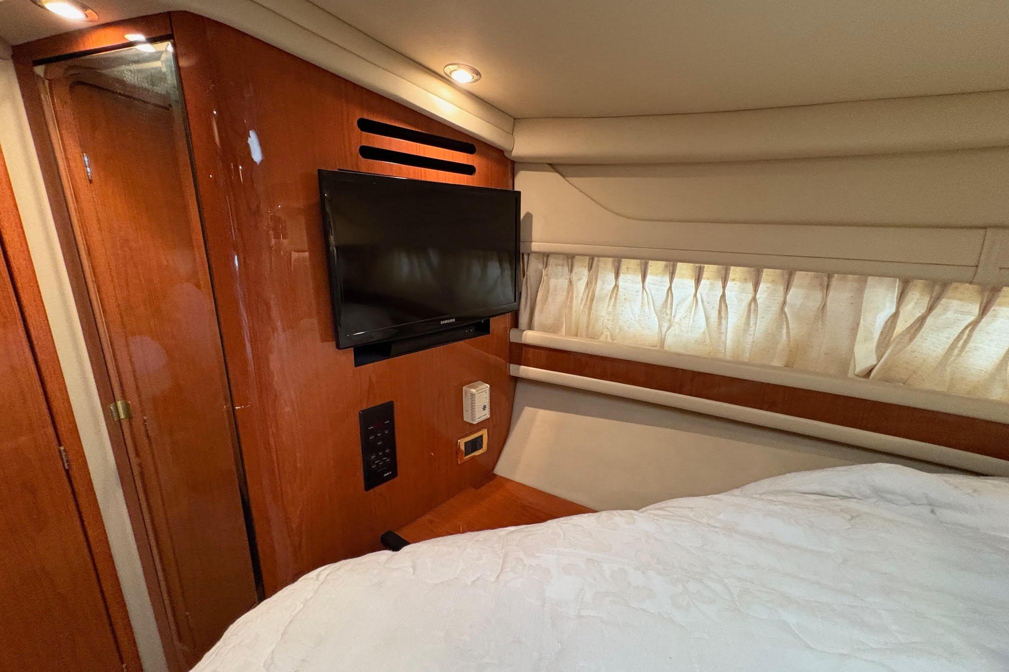 2001 Sea Ray 460 Sundancer cabin interior with TV, wood paneling, and bed.