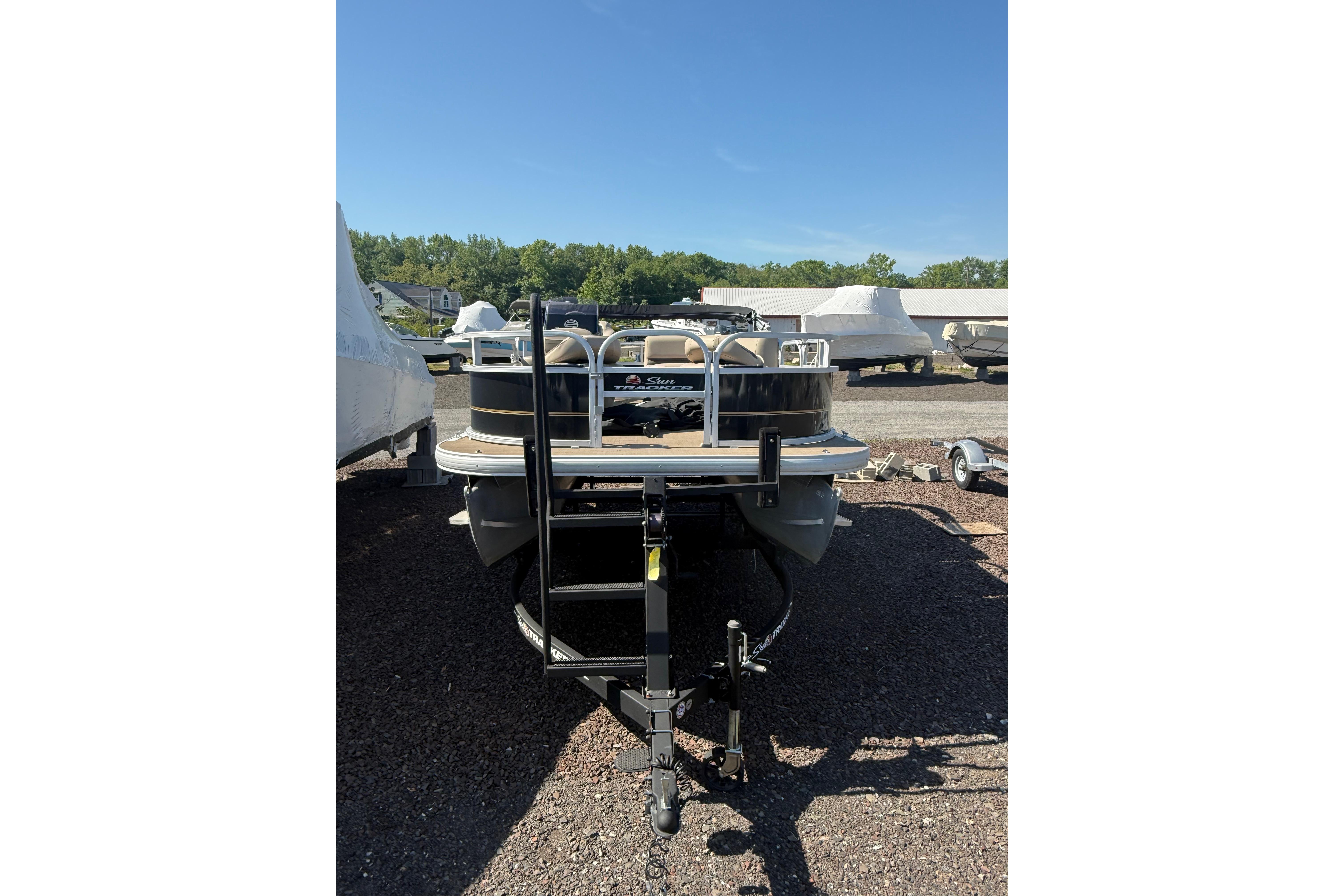 2021 Sun Tracker Bass Buggy 16 XL Select pontoon boat on trailer in outdoor lot.